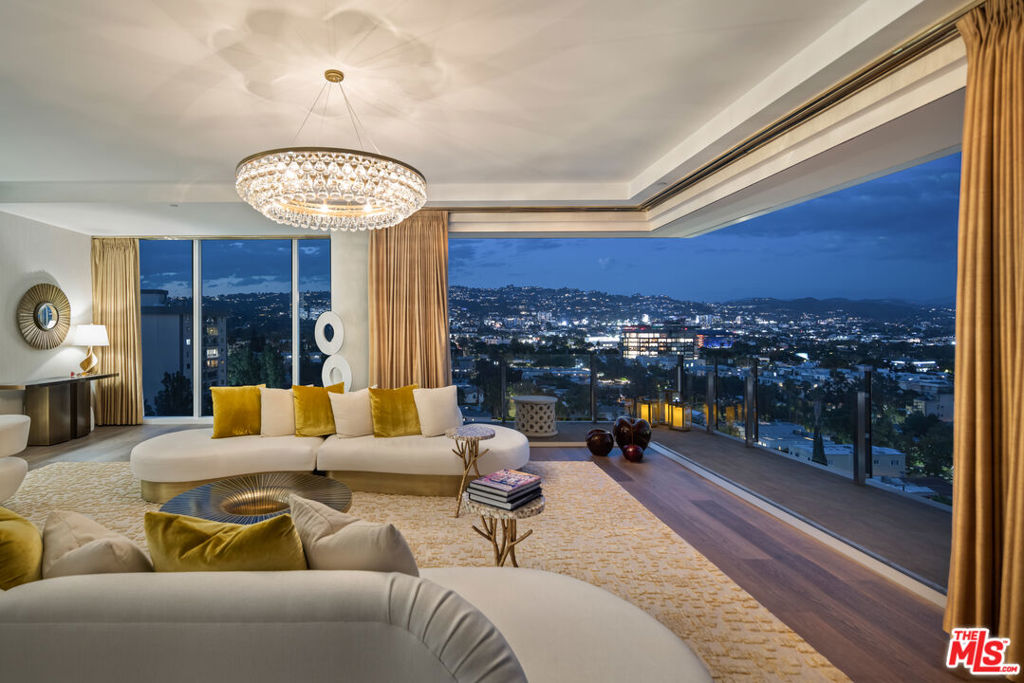 Set high on the 11th floor, this rare corner residence is not the penthouse yet lives with the presence of one, wrapped in glass and capturing spectacular views in every direction. A private dual elevator opens to an arrival foyer that sets the tone for more than 5,000 square feet of contemporary interiors suspended above the city and surrounded by floor-to-ceiling glass. Expansive living areas unfold with ease, framed by large wraparound balconies that capture sweeping vistas from downtown Los Angeles to the Pacific Design Center and Hollywood Hills. Light shifts throughout the day across the double living room, family space, and formal dining area, each flowing effortlessly into one another while maintaining a sense of scale and distinction. The kitchen is crafted as both a workspace and a retreat, with a large laundry, full bath, and flexible bonus room discreetly concealed behind. A richly composed powder room adds refinement, while ample storage is seamlessly integrated throughout. The primary suite is a sanctuary in its own right, commanding cinematic views that stretch across the city. Dual baths are individually appointed, including a soaking tub positioned before the skyline, accompanied by walk-in closets and a dedicated vanity area. Two additional guest suites, each with marble-clad baths and walk-in closets, also feature magical views both day and night. Life within this Four Seasons residence is matched by the service and environment beyond. With interiors by Martyn Lawrence Bullard, just fifty-nine homes share access to resort-style amenities: a pool framed by cabanas, a private restaurant with twenty-four-hour in-room dining, concierge and valet, and a dedicated property management team whose reach extends from safeguarding the residence while away to orchestrating a stocked kitchen or private jet on return. Set at the nexus of West Hollywood and Beverly Hills, moments from celebrated dining, shopping, and nightlife, it is a home that carries the rare equilibrium of architectural presence, five-star service, and absolute discretion.