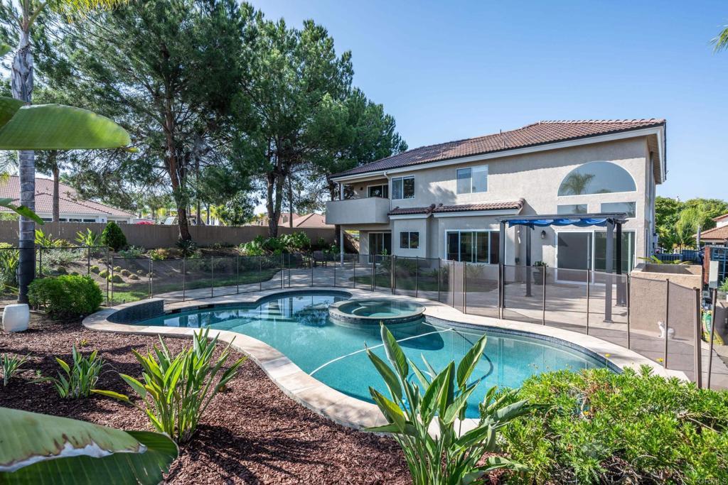 This stunning four-bedroom view home is perfectly situated on a corner lot, offering panoramic views of the surrounding hills, a spacious 3-car garage, and lush tropical landscaping surrounding a sparkling saltwater pebble pool. The large private yard includes a freestanding pergola and beautifully manicured grounds, creating the ideal outdoor space for entertaining or relaxing. Inside, soaring two-story ceilings and expansive, light-filled rooms create a bright and open feel. The home features four generously sized bedrooms, including a luxurious primary suite. Main living areas showcase updated lighting, durable Pergo luxury vinyl plank flooring, and new paint throughout. The open-concept kitchen overlooks the pool, offering the perfect backdrop for everyday living and seamless indoor-outdoor entertaining. Upstairs, the primary suite is a true retreat, complete with a private deck, a large walk-in closet, and a spa-inspired bathroom featuring dual vanities, a soaking tub, a new tiled shower, and a large walk-in closet. Recent improvements include a new HVAC system, a complete roof replacement, new appliances, 3 new sliding doors, and modernized finishes throughout. With thoughtful updates, elegant style, and breathtaking views, this move-in-ready home offers the perfect balance of comfort and sophistication.