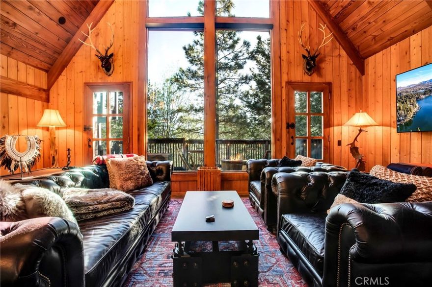 Welcome to your rustic mountain home styled as a nostalgic Prohibition themed retreat! What better way to step back in time but with modern amenities and a vibe that truly sets the scene. Built in the 1970s by Kenny Anderson. Recently renovated/curated with passion and intention by Swankitecture Properties. Drive up to this matte black structure with level entry and decks that engulf you in a secluded treehouse setting.

On the interior, custom artisanal woodwork draws you in. Hand carved archways and tall wood-beamed/cathedral-vaulted ceilings demonstrate unparalleled attention to detail. The living room features a massive window wall that shows you nature’s best. This eastern exposure is outfitted with a custom tint that blocks the heat during the warmer months and direct access to the rear decks for seamless entertainment.

The kitchen was reimagined as an open concept for entertaining with a blackened hot rolled steel fireplace as the focal point; from here custom ironworks and painted stenciling propagate throughout the home for a balanced industrial flair. Granite countertops, cedar shelving, a raw slate backsplash, repurposed factory pendants, custom floor lamps, and handcrafted light fixtures from whisky barrel staves make this home one of a kind.

The second level incorporates a versatile loft, two additional bedrooms, and the primary suite. The primary is a retreat within itself equipped with en suite, an intimate study, and a private observation deck. Finished with a beamed ceiling that includes a skylight, a giant river rock fireplace, and ample sitting room. The en suite is the epitome of luxury with a freestanding tub, step in shower w/ dual heads, and its own skylight.

The home’s exterior offers multiple vignettes for entertainment and personal escapes. Upper and lower decks, a centered hot tub perfect for stargazing, and dual propane fueled fire pits where one sits amongst the trees. Recently updated robust systems include James Hardie backer siding along the lower perimeter of the home, Trek decking, K-style rain gutters with Grade A leaf protection, Starview-20 solar film window tint, Skyco roller shades, and Nest Thermostat. There is even central AC. The current owner has used this as a successful vacation rental. Think twice before letting this one-off luxury lake rights home pass you by.