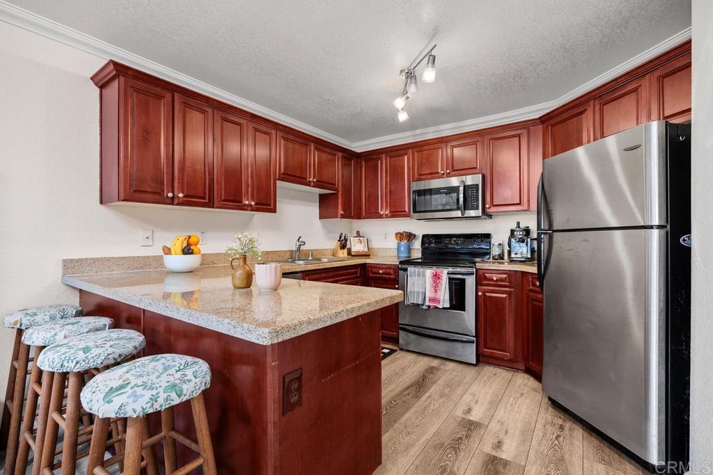 Welcome to Vista Way Village—a gated, peaceful, resort-style community offering comfort, convenience, and upscale coastal living. This 1,093 sq ft, 2-bedroom, 2-bathroom condo has been tastefully updated and is move-in ready! This TOP LEVEL UNIT enjoys a beautiful modern kitchen featuring rich cherry wood cabinetry, granite countertops, and stainless steel appliances. The open layout flows into a spacious living and dining area with luxury wood-style flooring, crown molding, and stylish lighting. A large peninsula counter is perfect for everyday dining or entertaining. Garden-style window nook—a peaceful spot ideal for indoor plants or relaxing with a view of the greenery outside. Interior Highlights: Updated kitchen with granite countertops & stainless steel appliances. Cherry wood cabinets with ample storage. Bright, open-concept living space. Crown molding and wood flooring. Cozy living room fireplace. Large bedrooms with walk in closet. 2 full bathrooms with modern fixtures. Large, private covered patio. In-unit laundry. 1 private garage + 1 assigned parking space. Vista Way Village Community Amenities: Gated community with controlled access. 2 sparkling pools & 2 relaxing spas. Large, fully equipped fitness center. Spacious event room with kitchen – perfect for hosting gatherings. Tennis court. Play area. Pet-friendly, lush landscaping, and walking paths. Prime location near shopping, dining, freeways, and just minutes to the beach.