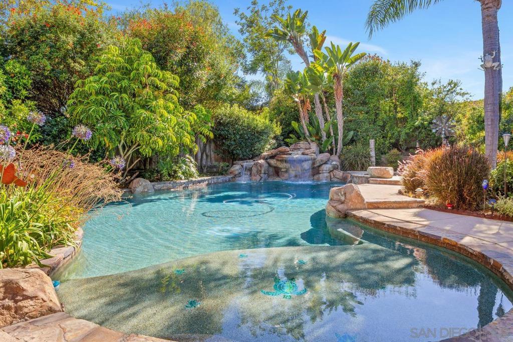 Set in the sought-after Vista San Luis Rey community, this stunning two-story retreat offers an extraordinary backyard paradise with a pristine saltwater pool featuring a Baja shelf, dramatic waterfall, and soothing in-ground spa surrounded by lush, mature landscaping. Inside, soaring ceilings and walls of windows flood the space with natural light, complementing elegant living areas and a bespoke wet bar. All perfectly situated on a tranquil cul-de-sac near vibrant dining, shopping, and parks. Top-rated schools nearby & quick access to Hwys 76, 78 & I-5. Conveniently located near the new Frontwave Arena, Mission San Luis Rey & local shopping/dining. Numerous updates incl. remodeled kitchen & baths, updated primary suite, refreshed fireplaces, crown molding, dual-pane windows, & roof replaced in 2018. Complete front yard, driveway & walkway remodel w/ pavers & waterfall feature (2022). Drought-tolerant landscaping w/ vibrant pollinator activity, plus highly productive orange & pomelo trees. The saltwater pool offers both solar and gas heating for comfortable, year-round enjoyment. An integrated spa invites relaxation with a full-body hydro-massage, strategically placed jets, and a tranquil spillway waterfall. A serene water curtain with a hidden seating ledge flows from the main pool waterfall, creating a peaceful retreat. In addition to the pool’s features, the property showcases three more stunning water elements: a dramatic 10’ x 10’ backyard fountain with jets that soar up to five feet, a timeless three-tiered fountain near the outdoor dining area, and a cascading waterfall at the front entry that sets an elegant tone from the moment you arrive. The home also includes E-pipe retrofitting, offering peace of mind with a modern, corrosion- and leak-resistant plumbing upgrade. Dedicated office w/ ample storage. Upstairs closet doors, front doors & butler’s pantry door replaced in the past 3 yrs. Primary suite deck fully rebuilt. Two skylights were replaced w/ clear windows during 2018 roof remodel for added natural light.