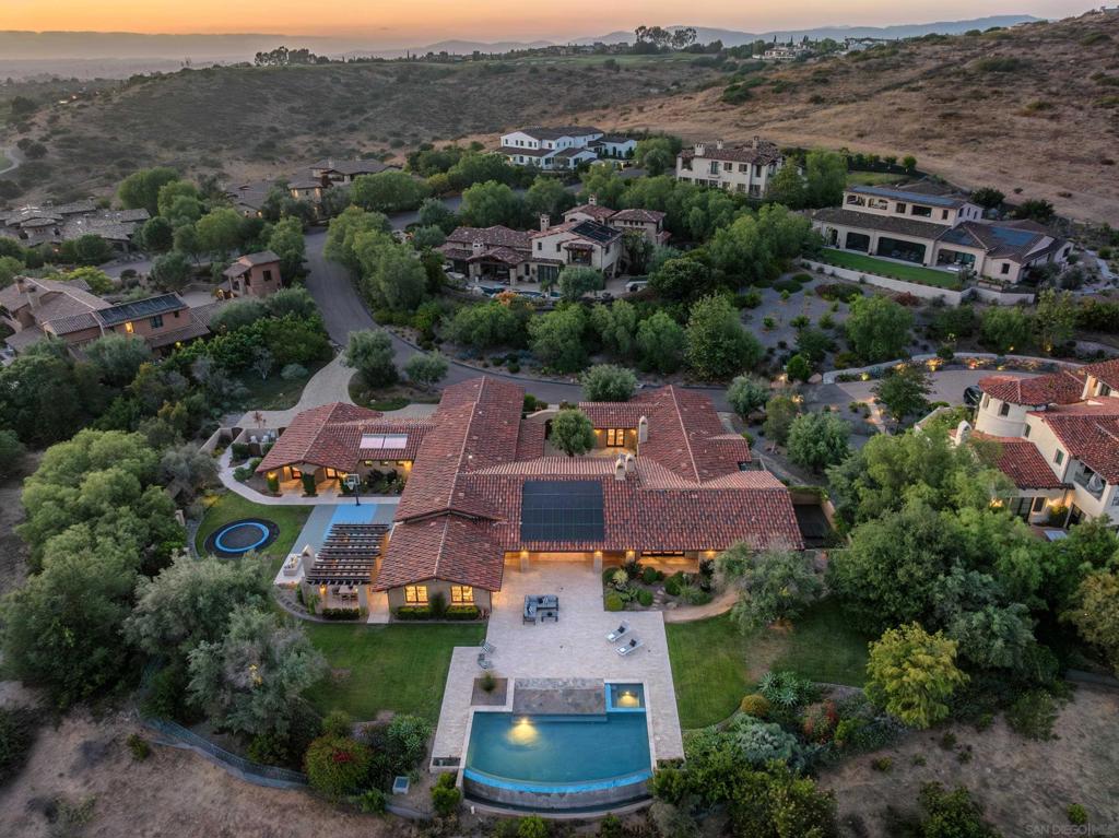 Discover a captivating custom-built estate in the coveted Santaluz community of San Diego. This single-level masterpiece spans 6,424 square feet, offering a seamless blend of luxury and comfort. Step into the welcoming courtyard, complete with a fireplace and fountain, and be transported to a world of elegance. The great room unveils panoramic southern exposure views over the vanishing edge pool and rolling hills. The gourmet kitchen connects effortlessly to the family room, bathed in natural light and complemented by an outdoor kitchen and play yard. The primary bedroom wing boasts a cozy fireplace, a spa-like bath with an outdoor hot tub, and a custom walk-in closet. Additional highlights include three ensuite secondary bedrooms, an executive home office, a home theater, and a guest house with a private entrance. Enjoy the allure of open spaces, a signature golf course, miles of hiking trails, and a top-rated school district. Live a life of refined luxury in Santaluz.