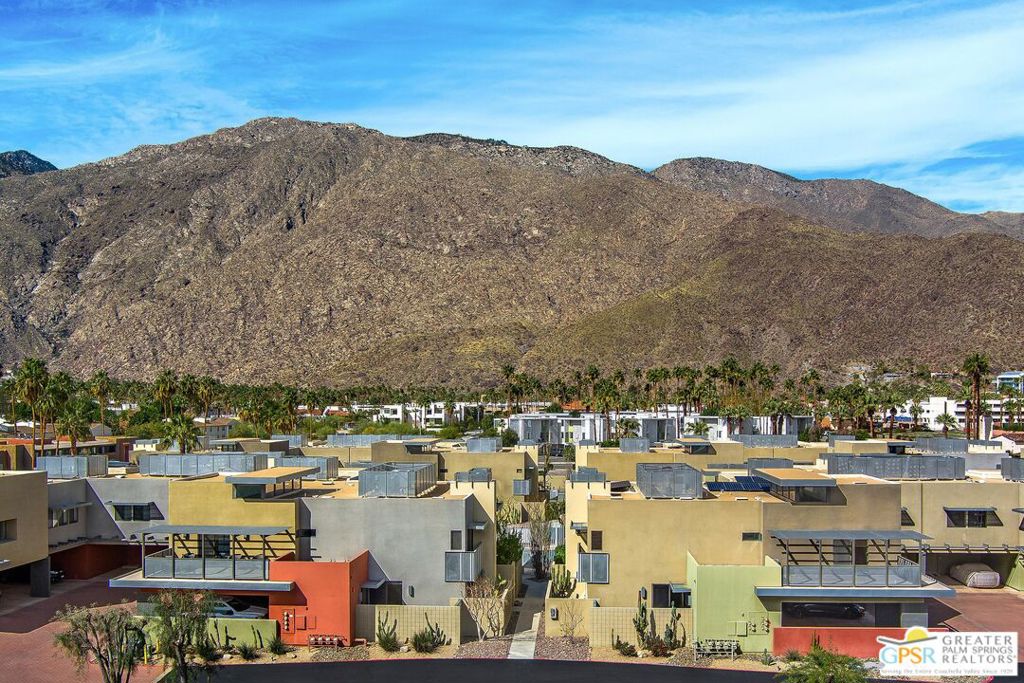 Amazing value! Fee simple land (no land lease), OWNED solar, and immaculate condition. Experience the best of Palm Springs living in this meticulously maintained modern townhouse, ideally situated in the heart of downtown, adjacent to the newly established Arenas District. Thoughtfully upgraded and offered for sale for the first time since construction, this home showcases striking, award-winning contemporary design. Highlights include 9-foot ceilings, a floating iron and wood staircase, a gas fireplace, and gleaming tile floors. The stunning kitchen boasts sleek cabinetry and appliances, pristine quartz countertops, and ample storage. Two spacious primary suites feature spa-like ensuite baths, with the south suite offering a large walk-in closet, a steam shower, and picturesque views of the pool and mountains. Enjoy the private, walled patio surrounded by lush greenery, complete with a built-in gas line - perfect for a fire pit, grill, or outdoor dining area. Additional upgrades include a Navien tankless water heater, a Carrier AC system, and a three-stage water filtration system. Other conveniences include two deeded covered carport spaces just outside the kitchen entrance, central vacuum, bicycle storage, and gated access. Located in the heart of downtown Palm Springs, this home offers effortless access to the city's best dining, shopping, and entertainment, including Sherman's Deli, the International Film Festival, the Convention Center, and Agua Caliente Casino. The HOA covers earthquake insurance, water, refuse, pools and spas, and roof maintenance, making this an exceptional lock-and-leave opportunity in the city's most vibrant district.