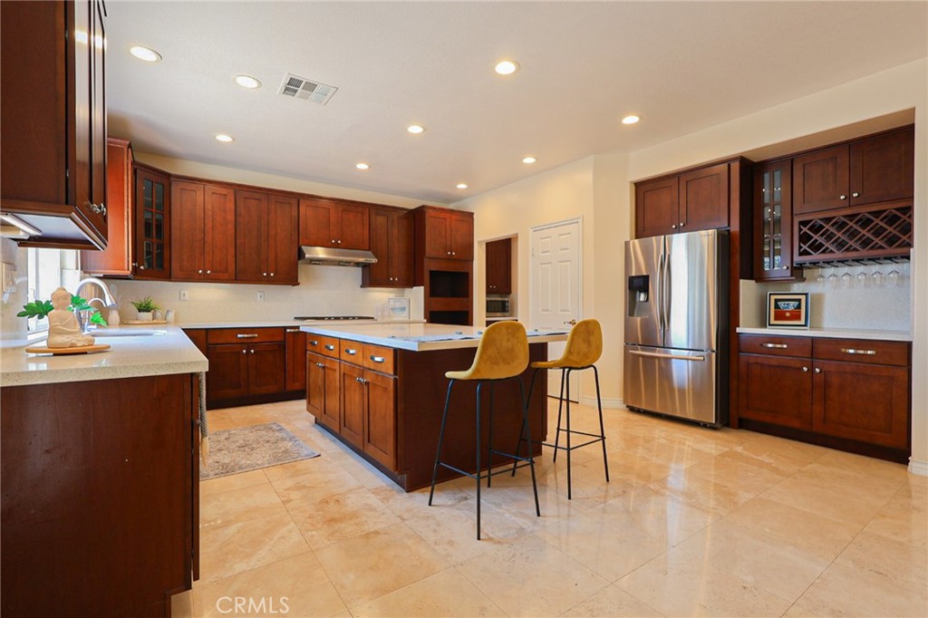 This meticulously designed 5-bedroom, 4-bathroom home offers an exceptional blend of luxury and function. Upon entry, you are greeted by 20-foot ceilings and polished travertine flooring that flows throughout the main level. The floor plan includes formal living and dining rooms, a dual-sided fireplace, and a desirable downstairs bedroom with a full bathroom. The gourmet kitchen is appointed with granite countertops, a massive center island, and a butler's pantry, opening to a spacious family room. A circular stairway leads to the second level, which hosts three full bathrooms and four additional bedrooms, including the expansive master suite. This private retreat features a large walk-in closet, a separate tub and shower with dual sinks, and a private balcony with a gorgeous view. The property is complete with a built-in backyard BBQ, a putting surface for recreation, and a 3-car tandem garage for ample parking and storage.