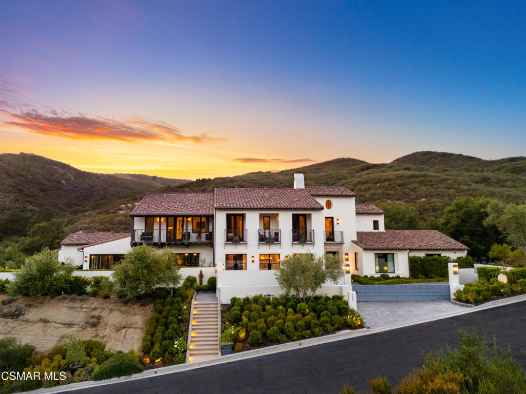 An architectural triumph gracefully perched within the exclusive, privately gated enclave of Country Ridge, this Calabasas estate is a showcase of artistry, luxury, and serene natural beauty. Featured as one of only seven prestigious residences, this custom Spanish Modern masterpiece commands attention with its meticulous craftsmanship, tasteful elegance, and remarkable setting against the majestic backdrop of the Santa Monica Mountains. Ideally located near Calabasas' sophisticated boutiques, acclaimed dining venues, and the sun-kissed beaches of Malibu, this property seamlessly blends premier convenience with secluded tranquility.Upon entering, guests are immediately captivated by the residence's distinctive architectural elegance, from the grand foyer to the dramatic living area, accentuated by a striking floor-to-ceiling linen-wrapped fireplace, meticulously detailed ceilings, and bespoke built-in cabinetry. Artistic, designer wallpaper adorns nearly every room, enriching each space with sophisticated textures and depth, distinguishing this home as a unique custom offering. Elegant fixtures throughout the home, sourced exclusively from Restoration Hardware's premier collections, enhance the atmosphere of refined luxury. The formal dining room and sunlit conservatory effortlessly extend to manicured gardens and patios, ideal for indoor-outdoor entertaining at its finest.At the heart of this distinguished residence lies a gourmet chef's kitchen, appointed with elite appliances from Wolf, Sub-Zero, and ASKO. An impeccably designed catering and butler's pantry provides unmatched practicality and sophistication for both grand events and intimate occasions. The adjacent expansive great room and comfortable sitting area flow seamlessly to the lush outdoor spaces, blending casual comfort with refined luxury.Ascending the elegant staircase, the upper level reveals five beautifully designed ensuite bedrooms, a stately library, and an inviting den. The luxurious primary suite serves as a serene sanctuary, featuring bespoke wall coverings, a private viewing balcony, and a spa-like bathroom with indulgent amenities including a soaking tub, steam shower, private water closet, and striking Walker Zanger tiles.Four additional ensuite bedrooms offer superior comfort and thoughtful design, completing the second floor's elegant layout.The home's outdoor spaces present an entertainer's paradise, with a sophisticated resort-inspired pool, expansive barbecue area with a dining bar, lush California Turf, and tranquil Zen gardens. Multiple terraces and thoughtfully arranged seating areas invite alfresco dining, relaxation, and contemplation, all framed by breathtaking canyon and ridgeline vistas.A testament to refined living, unmatched craftsmanship, and visionary architectural brilliance, this estate epitomizes the essence of luxurious Southern California living, worthy of distinction in the pages of top architectural and lifestyle publications.