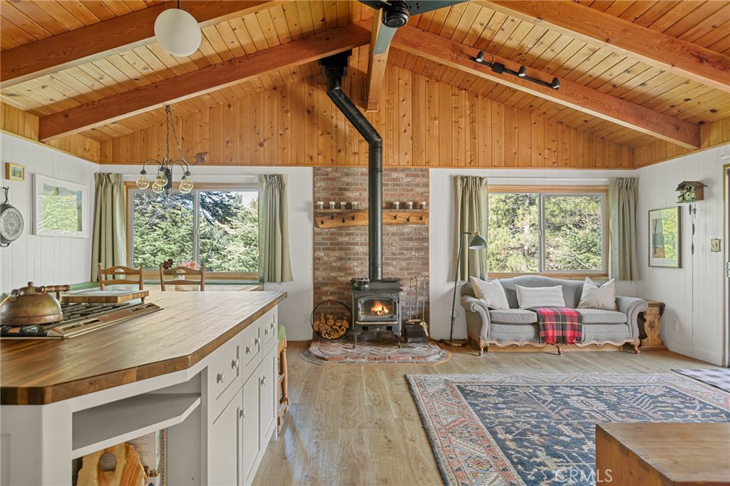 This updated, darling cabin is the perfect blend of mid-century charm and modern upgrades. It is located in the enchanting mountain community of Green Valley Lake, at an elevation of 7200ft, that offers year-round fun from swimming in the lake and trout fishing from your rowboat during the warm summer months to skiing on the nearby slopes of Snow Valley during the winter. The property is a stone's throw from the lake, and features a gentle sloping driveway with ample parking and just a couple of steps up to the front door. Once inside, the lower level presents a large living room with brick fireplace for those cozy cold nights (pool table included), a bedroom with a spacious walk-in closet and en-suite bathroom, a storage room, as well as the laundry and utility room. Upstairs is the main living level with a fully remodeled kitchen featuring a large island with butcher block countertop, a GE Cafe double oven and range, abundant cabinet space, Carrara marble countertops, custom light fixtures and a quaint dining nook. The kitchen opens to the main living room, which is the heart of the home with a striking vaulted ceiling, a heat efficient wood burning stove and unobstructed views of the surrounding forest without any neighboring homes in sight. A slider opens onto the top deck - the perfect spot to take in the beautiful setting of the home. Also on this level are 2 additional bedrooms and a full bathroom. Recent upgrades include: newer furnace, upstairs wood burning stove, seamless open gutters with hot wires, a whole house fan, new electrical panel with manual transfer switch for a generator hookup and waterproof hybrid flooring throughout common spaces. Do not pass this captivating cabin up! It is a must-see!