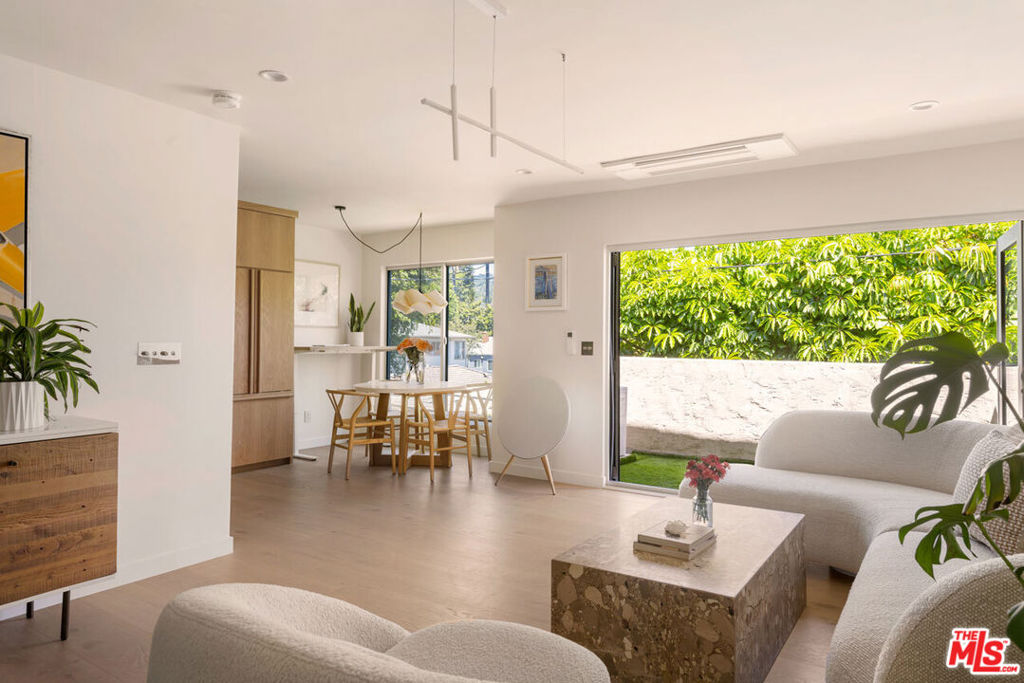 In West Hollywood's coveted Norma Triangle, this top-floor corner residence is a luxurious urban retreat, a sanctuary you've been seeking, with exquisite finishes and verdant views. Set within a gated courtyard building, the light-filled home presents a spacious great room with seamless indoor-outdoor flow; a folding glass wall expands the living space to a wraparound balcony overlooking treetop vistas and city lights. Italian white oak flooring and cabinetry, Italian marble countertops, and Forbes & Lomax switchware are just some of the refined details. The kitchen is outfitted with Fisher & Paykel appliances and a Bosch dishwasher, plus a built-in desk with matching oak surface. The bedroom enjoys balcony access and a custom white oak walk-in closet; the spa-like bath is finished in marble with double sinks, oak cabinetry, and a soft-lit mirror framing your best looks. With no shared walls,updated windows, and discreet mini-splits, this sophisticated haven puts you just moments from Melrose boutiques, Soho House, the Troubadour, and all the energy of Sunset Boulevard. Convenient parking options include a dedicated garage space plus street parking permits for your guests.