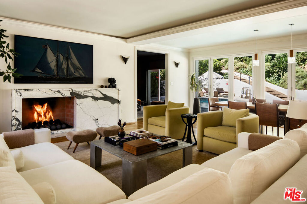Welcome to this exquisitely reimagined 1938 residence, a timeless retreat nestled in the heart of Outpost Estates at the base of the Hollywood Hills. This designer-done estate masterfully blends Old Hollywood glamour with modern sophistication, offering a rare fusion of architectural integrity and contemporary luxury. Behind its romantic, historic faade lies a fully transformed interior, where no detail has been overlooked and no expense spared.The home unfolds across 4,207 square feet of refined living space, framed by natural textures and ultramodern finishes. A grand living room sets the tone with its striking Paonazzo Corchia marble fireplace, flowing seamlessly into an elegant dining area perfect for hosting. The chef's kitchen, with its own integrated coffee pantry, pass-through window and custom temperature-controlled wine cellar are ideal for curated entertaining.The spacious bedrooms all include custom designed closets, and with the six luxurious bathrooms, you're provided with flexibility for both family living and comfortable guest accommodations.A row of French doors open wide to reveal a resort-like backyard oasis, lushly landscaped and framed by mature palms and rose bushes. An outdoor kitchen with pizza oven, sparkling pool, fire pit, and expansive patios invite effortless indoor-outdoor living. Whether you're enjoying a quiet morning coffee or a lively evening under the stars, every corner of this estate feels like a curated escape.Additional highlights include the option to purchase the home fully furnished. With its mix of one of a kind vintage furniture, collectible contemporary, and bespoke pieces that are designed specifically to fit the space - It's a true turnkey opportunity. Set on an impressive 11,355-square-foot lot, the property offers a rare sense of privacy while remaining moments from the pulse of the city.A captivating expression of historic charm and modern elegance, this Outpost Estates gem is more than a home - it's a lifestyle.
