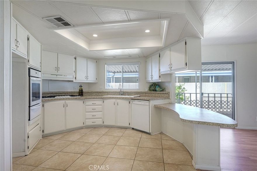 Must See! Desirable Gated Sun City Mobile Home Estates, a 55+ gated community, this double-wide mobile home features 2 bedrooms, 2 bathrooms, one of the bathrooms is a Jack and Jill bathroom, and approximately 1,440 sq. ft. of living space. Highlights include lots of natural light, a spacious primary suite with large closet space, soaking tub, walk-in shower, a formal living room and dining area with a built-in cabinet, and a great kitchen equipped with a gas cooktop and walk-in pantry with plenty of storage. Additional features include ceiling fans, a covered porch, a dog ramp and dog play area, and a nice covered carport with two large storage sheds. Enjoy the community amenities: a clubhouse, heated pool, and many social activities to give you lots of opportunities to get involved. Conveniently located near shopping, a hospital, and the 215 freeway. Great opportunity to live a simple life in beautiful Sun City Mobile Home Estates.