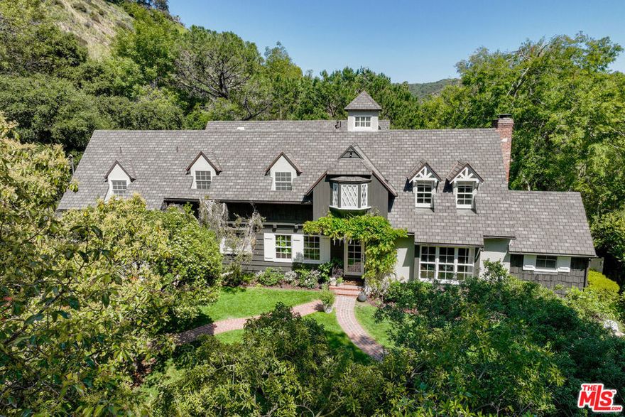 This stunning 1930's East Coast traditional sits up a gated drive in lower Nichols Canyon. A lush and private setting on a tree filled knoll of more than 2/3 of an acre; a true oasis just moments from the center of it all. Impeccably restored, classic yet modern interior spaces with family room opening to living room, dining room & brilliant cooks kitchen w/large center island, Viking stove, Sub-Zero's & more. Hardwood floors, original moldings, beamed ceilings, and two brick fireplaces. Ascend the curving Magnesite staircase with windowed Cupola overhead to the four upstairs bedrooms including a master suite with luxurious bathroom and two walk-in closets. An additional guest/maid suite is located on the first floor. Oversized French Doors open out to the expansive rear grass yard and gardens that are perfect for entertaining or family adventures. A private gated pool and cabana with bath located at the end of a meandering path completes this incredibly charming home. Located just moments from Hollywood but feels a world away. Lot size includes additional parcel, APN:5569-003-009