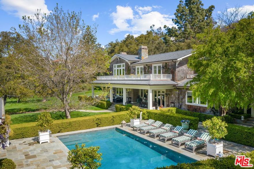 Set upon more than 2.3 acres of lush grounds in Rustic Canyon, this grand Hamptons-style estate evokes an elevated design sensibility among an ultra-secluded setting that cannot be found elsewhere in Pacific Palisades. Featuring 8,162 SF of living space among a main home, guest house and pool house, the estate is replete with sophisticated details, high-beamed ceilings, wood floors and spectacular views over the luxuriant grounds. Offering remarkable living spaces, the main home includes formal dining, two living rooms, library, media room and gourmet chef's kitchen with a marble island, all opening to an immense front porch set to rolling greenery views. The grand primary suite showcases vaulted ceilings, its own balcony, sitting room, fireplace, and two closets and spa baths. A true oasis with sprawling lawns and immaculate landscaping, the estate's picturesque outdoor setting features a mature David Austin rose garden with 100+ English roses, an impressive kitchen garden that produces seasonal vegetables, fruits and herbs, an expansive apple orchard, abundant citrus trees, bocce ball court, pool and spa with an outdoor kitchen and pool house, and guest home with its own front porch and kitchenette. A truly one-of-a-kind property in Los Angeles, this Rustic Canyon estate is the ultimate setting to realize your most legendary, secluded compound.
