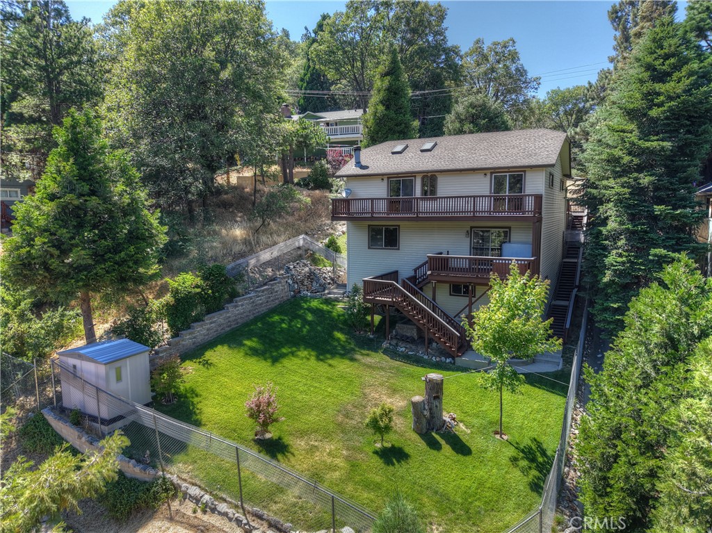 This gorgeous 3-bedroom, 2-bathroom 1,452 sq ft home is conveniently located within walking distance to Crestline’s scenic Lake Gregory and popular yoga studio. It features multiple upgrades and is nestled on a beautiful picturesque 5,550 sq ft USABLE lot. One of the few Crestline homes with a completely grassed and fully fenced backyard. Featuring an impressive 15-foot Blackberry Bush, Japanese Maple Trees, storage shed, and Rock Waterfall & Pond. The beautifully maintained backyard can be enjoyed from all multi-level decks and all three bedrooms. The home has stunning Koa Brazilian hardwood floors on all levels. A 6-year-old shingled roof with a 30-year warranty, vinyl siding, 2 levels, extra storage, a septic, & 3 parking spaces. There are beautiful, vaulted living room ceilings with remote control skylights. An automatic Generac standby generator offers power during severe storms and blackouts. Newly stained 2-car deck parking for convenient level front door entry. The front porch has a beautiful Cherry Tree with four different cherries and an Apple Tree with seven different apples. The Main Living Room features remote skylights and a Rock Wall Gas & Wood Fireplace. Enjoy the quiet living space with dual-pane windows throughout the home. The kitchen has new butcher block counters, outside the kitchen window is a beautiful rose garden and fruit trees. The top floor has a full bathroom with custom shelves across from a large bedroom, with access to your own back deck shared with the main living space, the length of the home, with wide-open space and beautiful views. The 2nd level has a laundry closet with cabinets, washer, & dryer. The full bath has heated floors, two sinks, and beautiful marble counters. The primary bedroom has his and her closets, one of which is a custom-built 7 by 12 ft walk-in closet. Just outside the primary bedroom, you can enjoy and relax to the forest sounds, wind, bird songs, and mountain views in a 4-person well-maintained covered Jacuzzi with access to the fully fenced grass backyard. The 3rd room is also big and has open views and peaceful sounds next to the waterfall and pond. The lower level features a 13 by 22 bonus room with extra storage space. The backyard area has also been used for meditations, yoga, and for kids, cats, and dogs to play in. The home boasts remarkable sunsets, starry nights, and mountain views, making it an ideal setting for those looking to embrace serenity, safety, and mountain home living.