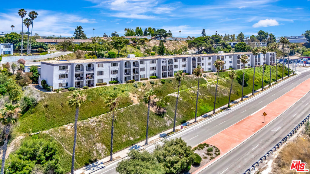 Welcome to this 2-bedroom, 2-bathroom condo in a 55+ community. This home offers a modern layout with appealing views that enhance daily living, making it an ideal choice for those seeking a comfortable and convenient lifestyle. The open living area features wood floors and neutral walls, with large windows showcasing greenery, palm trees, and a view of the coastline and distant hills, providing a serene backdrop for relaxation or quiet moments. The space is well-suited for entertaining or unwinding, with ample room to arrange furniture to suit your needs.The kitchen includes stainless steel appliances, white cabinets, and an island that offers additional workspace. The dining area connects seamlessly with a sliding door that allows natural light to brighten the space, creating an inviting atmosphere. The primary bedroom provides a quiet retreat with wood floors and a relaxing bathroom, offering a private space to unwind after a long day. The second bedroom serves well as a guest room or office, with another bathroom nearby. A baseboard heater ensures comfort on cooler days, adding to the home's practicality. The balcony offers a view of flowering shrubs and the palm-lined highway, providing a pleasant spot to enjoy the outdoors or take a moment to yourself. This condo is designed with the needs of active adults in mind, offering a low-maintenance lifestyle. Located in Oceanside, it provides easy access to local amenities and a peaceful setting that balances relaxation with convenience.