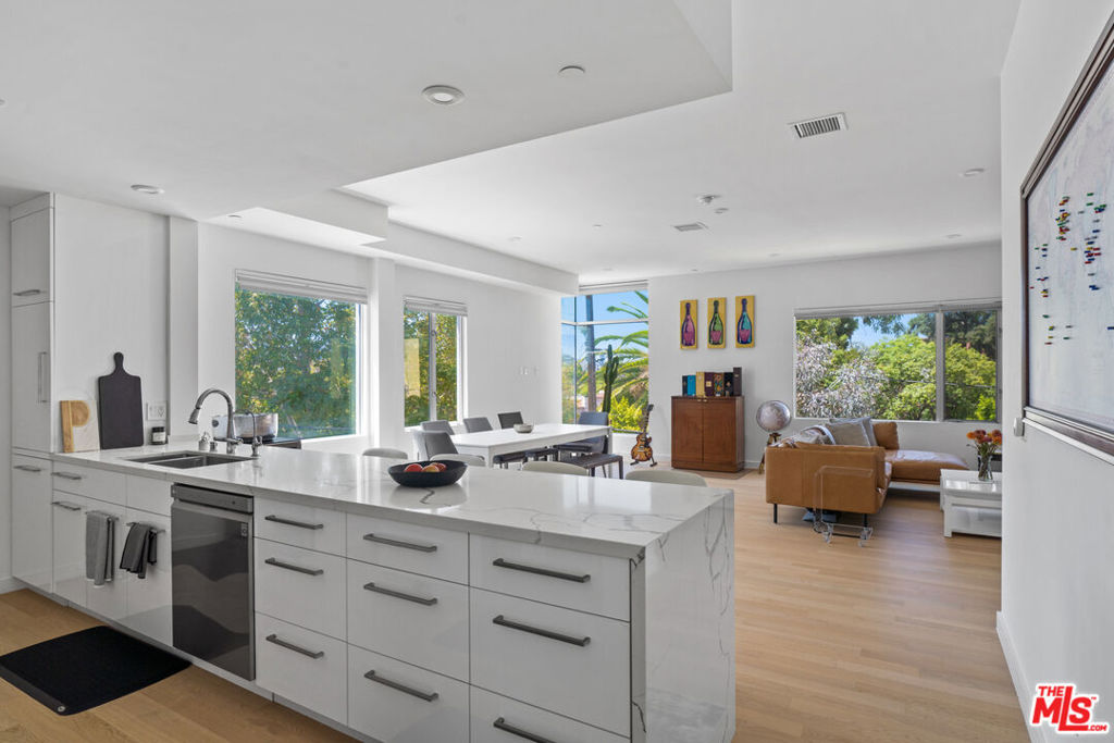 Modern two-bedroom residence with two outdoor spaces, including a private rooftop deck boasting panoramic views of the Hollywood Hills and iconic Hollywood sign. The primary suite features a balcony overlooking a palm treelined street, black out shades and in addition there are sunshine blinds. While both bedrooms offer ensuite, marble stone spa-like baths. No shared/common walls provide rare privacy, and high-end finishes shine throughout with European wood plank floors, Bosch appliances, Kohler fixtures, custom soaking tub, and electric hands-free blinds and high ceilings. Two subterranean side by side parking spaces included with one EV Charging station in one of the spots. This home offers modern luxury in the heart of West Hollywood, just moments from Melrose Place, Beverly Center, top dining, and the Pacific Design Center.