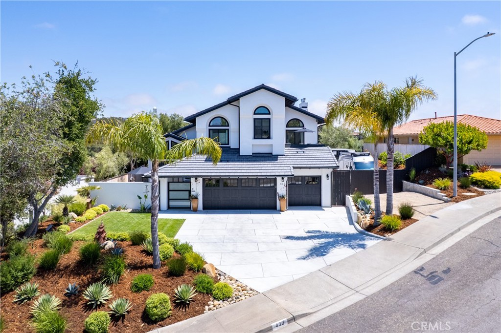 Experience modern Mission-style living in this beautifully reimagined home located on a peaceful cul-de-sac in the heart of Arroyo Grande. Originally built in 1989 and completely renovated in 2023-2024, this turn-key residence blends timeless architecture with luxurious contemporary upgrades.
From the moment you arrive, the home's stunning curb appeal captures attention, featuring fresh landscaping with drought-tolerant plants, a vibrant green lawn, swaying palms, a brand-new concrete driveway, and a three-car garage with stylish new doors. A private front patio offers a welcoming space to relax and enjoy the serene surroundings. Inside, you’ll be greeted by soaring 20-foot vaulted ceilings, a striking custom staircase, and abundant natural light flowing through the open-concept living and dining areas—perfect for entertaining and everyday living. The chef’s kitchen has been fully remodeled with quartzite waterfall-edge countertops, a full-height designer tile backsplash, custom white oak pantry, soft-close custom cabinetry, and luxury GE Café appliances. The main level includes a spacious guest bedroom and a beautifully finished full bathroom. Upstairs, the expansive primary suite features its own fireplace, private balcony with ocean views, and a spa-inspired ensuite bathroom with a large Carrara marble walk-in shower, soaking tub, and walk-in closet. Two additional bedrooms—one with a balcony—and a versatile flex-space offer plenty of room for guests, hobbies, or a home office. Every bathroom showcases high-end finishes including quartz countertops, custom cabinetry, designer tile, and premium fixtures. French doors open to the private backyard retreat, complete with a spacious deck, lush lawn, hillside views, and room to entertain. A gated side yard provides RV or boat parking. The home's upgrades include a new concrete tile roof, central air conditioning, Milgard windows, tankless water heater, new furnace, updated plumbing and electrical, luxury vinyl plank flooring, and fully redesigned landscaping with an additional detached flex-space for a gym or office. This is a rare opportunity to own a truly move-in-ready designer home with ocean views, in one of Arroyo Grande’s most desirable neighborhoods.