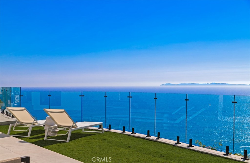 Introducing one of the most spectacular brand-new construction offerings in all of Laguna Beach — a soft contemporary estate nestled within the ultra-exclusive guard-gated enclave of Three Arch Bay. Perched on a nearly 28,500 square foot lot, this architectural triumph offers 5,223 square feet of open-concept living space, breathtaking panoramic ocean views, and a level of privacy rarely found on the coast. This estate stands as a testament to vision, patience, and craftsmanship. Engineered around a massive retaining wall and constructed to the highest standards, this is a build that may never be replicated or seen again in coastal Orange County. A long, private driveway leads to a stunning multi-level facade wrapped in crisp white modern lines and expansive glass. An oversized garage with 9-foot doors and over 10-foot ceiling height provides ample space for luxury vehicles and storage—perfect for car enthusiasts. From the garage level, a private elevator offers seamless access to all floors, ensuring effortless transitions throughout the home. Inside, walls of glass seamlessly disappear to merge indoor-outdoor living, unveiling sweeping views of Catalina Island and the Pacific. The chef’s kitchen features a European-style design, top-tier appliances, and a massive island ideal for entertaining. The great room boasts soaring vaulted ceilings, creating an airy, open feel that enhances the home’s impressive scale. The spa-like primary bathroom offers a luxurious retreat, with ocean views from both your soaking tub and the steam shower, which features a built-in relaxation bench—perfect for unwinding and taking in the endless ocean vistas. Step outside to expansive view terraces, a built-in outdoor kitchen, firepit and a pristine spa that invites relaxation with the ocean as your backdrop. Two generous bonus rooms offer flexible space for a gym, office, storage and or wine cellar. Residents enjoy exclusive access to a private beach with natural tide pools and dramatic coastal arches, along with community amenities including tennis courts, a clubhouse, and 24/7 security. Perfectly positioned just minutes from downtown Laguna Beach, world-class resorts, fine dining, and top-rated schools, Three Arch Bay is one of Southern California’s most sought-after coastal communities — where privacy, luxury, and natural beauty converge.