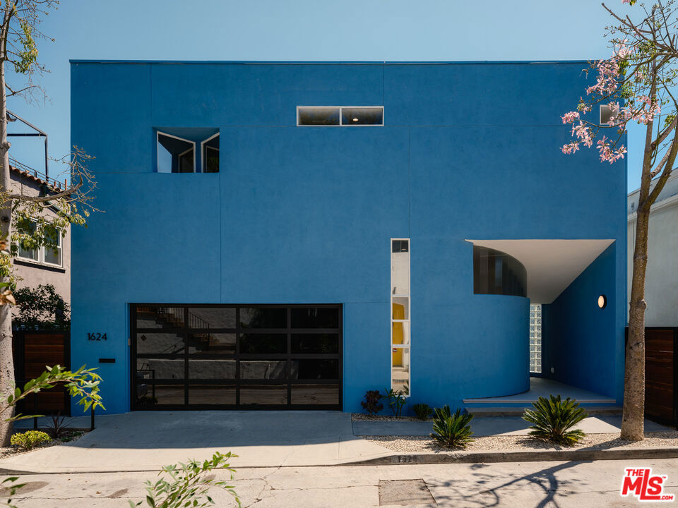 A true work of modern architecture, this Silver Lake marvel was designed in 1989 by J. Frank Fitzgibbons, AIA. Celebrated for its bold geometry and dramatic volumes, the residence has now been fully remodeled with refined Scandinavian-style finishes. Situated in one of Silver Lake's most sought-after enclaves, the home is moments from acclaimed shops, dining, and the vibrant cultural energy that defines the neighborhood. Inside, soaring ceilings and a procession of skylights create a dynamic interplay of light and space. A sweeping staircase serves as the home's dramatic centerpiece, while expansive windows and balconies open the interiors to the surrounding environment. The Scandinavian-inspired design marked by clean lines, natural textures, and a serene palette amplifies both warmth and sophistication. The home features three generous bedroom suites, including a primary suite with dual closets, plus a versatile den ideal for a home office or creative space. Direct access to the two-car garage provides convenience and functionality, complementing the home's thoughtful layout. Every detail has been carefully updated to reflect modern living while honoring the home's architectural roots. Adding extraordinary versatility, the property also includes a detached duplex at the rear of the lot, discreetly positioned on 1625 Rendall Place. Comprising two one-bedroom / 1 bathroom units totaling 1,140 square feet and accompanied by three enclosed garages, this private secondary structure offers exceptional income potential while remaining entirely separate from the main residence.