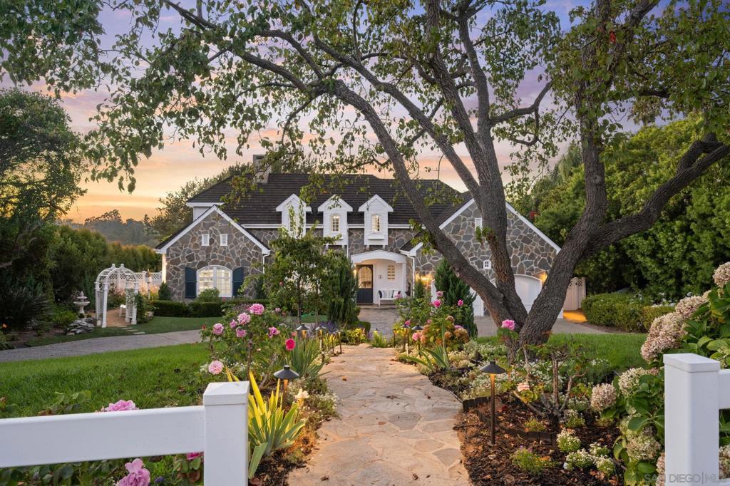 A perfect blend of timeless East Coast charm with relaxed Southern CA Living! The home is set on a generous usable lot with Panoramic Countryside Views & Sunsets, incredible gardens, and grass yard all delivering scale, privacy, and proximity to the Village, golf, beaches, and award-winning schools. The interior and exterior are full of generous "sun kissed" spaces with French doors that frame the entire back wall, inviting year-around indoor/outdoor living. The luxurious primary suite offers lovely vistas, large walk-in custom closet and grand spa bath with lovey views over the gardens. Each room offers total privacy and an incredible setting. The kitchen looks like a page out of Veranda Magazine and is equipped with Thermador, SubZero Refrigerator and Freezer, dual ovens, walk-in pantry, and large center island open to casual dining which flows seamlessly outdoors, where an expansive brick terrace, gardens, and covered loggia with fireplace extend living space year-round. The yard can easily accommodate a detached ADU with separate entrance for guests or family members. This property is so beautiful and unique ~ won't last long!