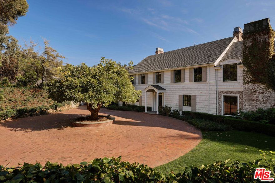 Originally built in 1938 for Hollywood actress Virginia Bruce, this gated Pacific Palisades estate is a rare blend of Old Hollywood glamour and modern luxury. Set at the end of a quiet cul-de-sac, the 7-bedroom, 8-bath residence spans over 8,000 square feet on more than 1.5 acres of lush, landscaped grounds. Manicured lawns, koi ponds, and meandering garden paths surround a pool, spa, and firepit, creating a true private compound.Inside, timeless East Coast architecture meets updated sophistication, with a Calacatta Gold marble kitchen, formal living and dining rooms, a British pub with hidden staircase, and a full guest apartment. The primary suite features dual bathrooms, custom dressing rooms, and a private balcony overlooking the gardens. Combining privacy, history, and luxury, this exceptional Pacific Palisades home offers a secluded retreat moments from Palisades Village and the co