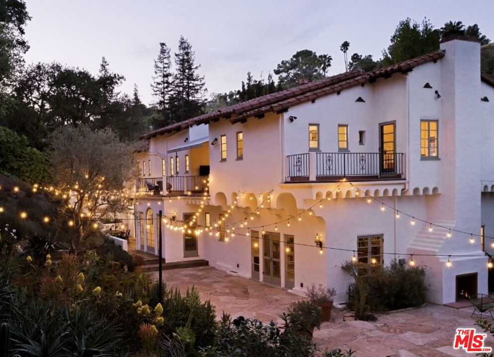 On a prime street in lower Los Feliz Oaks, just steps from Griffith Park, this refined Spanish Colonial Revival is a timeless amalgam of architectural artistry and sensitively updated modern convenience. Designed by notable architect Theodore J. Scott and built for developer Maurice Korman in 1928, the home showcases rich original details such as intricate plasterwork, hand-painted ceilings, hand-carved doors and beautiful built-ins. Step into a grand formal double height entry, where a sweeping wrought-iron staircase sets the tone and a quatrefoil window bathes the space in light. Note the patina on the original terracotta tile flooring and the Moroccan tile on the stair risers. The large barrel vaulted living room is anchored by an ornate fireplace and opens via french doors to the outdoors. A formal dining room is currently utilized as a family room and the new kitchen features custom cabinetry, quartzite counters, Fisher + Paykel appliances, a cozy breakfast nook and opens out to an outdoor dining and BBQ area. There is also a home office on this level with a soothing garden view. Upstairs, the primary suite is a tranquil retreat with private balcony, serene garden views and walk-in closet and dressing room. Two spacious guest bedrooms and an outdoor covered veranda complete the upper level. All the bathrooms upstairs feature wonderful original tile work. On an oversized double lot, the grounds are a peaceful retreat shaded by oak and olive trees. The topography of the site creates excellent privacy and there is room for a pool if desired. The outdoors truly feels like your own private park and it's also a terrific space for entertaining. There are numerous outdoor seating areas and lush gardens of succulents and native plants, along with views of the iconic Observatory. The home features upgraded plumbing, electrical, dual zone HVAC, a two car garage and large finished basement. Conveniently situated near the restaurants and shops of Los Feliz Village, Lazy Acres market, summer concerts at The Greek Theater and the hiking trails of Griffith Park, this singular historic home is an inspiring sanctuary in one of Los Feliz's most sought after neighborhoods.