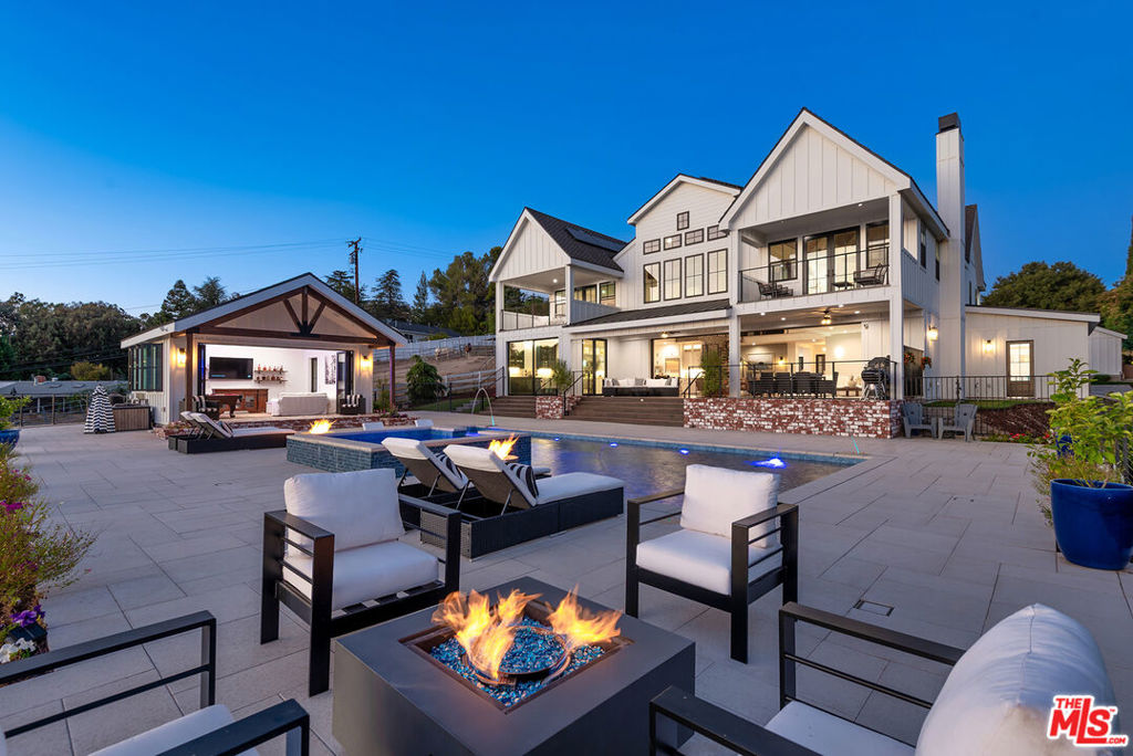Experience luxury country living in this stunning modern farmhouse estate atop a gated acre in Thousand Oaks. With panoramic canyon and mountain views, this equestrian property blends rustic charm and contemporary design featuring 2story vaulted ceilings, wide plank floors, steel-framed windows, and designer finishes. The open layout connects a state-of-the-art chef's kitchen to light-filled living spaces with sliding pocket doors that lead to a resort-style backyard with pool, spa, fire pit, pool house, plus an outdoor kitchen with pizza oven, BBQ, and smokers. Wonderful primary retreat with sumptuous bath, large walk-in closet w/ center island and private balcony overlooking views. 3 additional en suite bedrooms upstairs. Equestrian amenities include fenced paddock, 2 unfinished barns ideal for tack room/horse stalls, and trail access. An office, maids/guest suite, mini putting green and a fully equipped 1 bed +1 bath rec room with kitchen completes this rare trophy estate just minutes from the city.