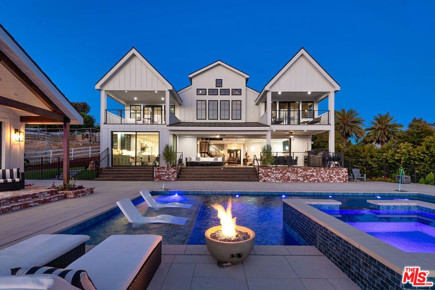 Experience luxury country living in this stunning modern farmhouse estate atop a gated acre in Thousand Oaks. With panoramic canyon and mountain views, this equestrian property blends rustic charm and contemporary design featuring 2story vaulted ceilings, wide plank floors, steel-framed windows, and designer finishes. The open layout connects a state-of-the-art chef's kitchen to light-filled living spaces with sliding pocket doors that lead to a resort-style backyard with pool, spa, fire pit, pool house, plus an outdoor kitchen with pizza oven, BBQ, and smokers. Wonderful primary retreat with sumptuous bath, large walk-in closet w/ center island and private balcony overlooking views.  3 additional en suite bedrooms upstairs.  Equestrian amenities include fenced paddock, 2 unfinished barns ideal for tack room/horse stalls, and trail access. An office, maids/guest suite, mini putting green and a fully equipped 1 bed +1 bath rec room with kitchen completes this rare trophy estate just minutes from the city.