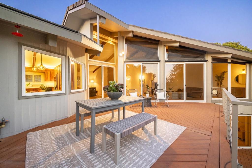 Tucked behind lush terraced gardens on a quiet street in Pasatiempo, this 5BR/4BA, 3,585 sq ft custom home offers stunning indoor-outdoor living w/ unexpected scale & serenity. A massive wood door opens to soaring ceilings, walls of glass, & expansive decks that span the length of the home, all overlooking sunny open space & tranquil natural views. The layout offers excellent separation of space w/ comfortable flow, flexible options for guests, home office, in-laws, or multi-gen living. On the main level: a spacious living room w/ fireplace & new flooring, formal dining area, open kitchen w/ koa wood cabinetry, granite counters, double ovens, five-burner gas stove, bar seating, & informal dining. A separate office w/ full bath & a generous primary suitecomplete w/ skylight, sitting area, & jacuzzi tubare also oriented to morning light & privacy. Downstairs features additional bedrooms, a shared bath, a separate guest suite w/separate entrance & a large family room w/ fireplace and its own deck overlooking a large flat yard. The Pasatiempo lifestyle blends timeless elegance & relaxed California living. Minutes from the coast & with quick access to Hwy 17, this home offers quiet retreat & modern comfort in one of Santa Cruz Countys most sought-after gated enclaves.