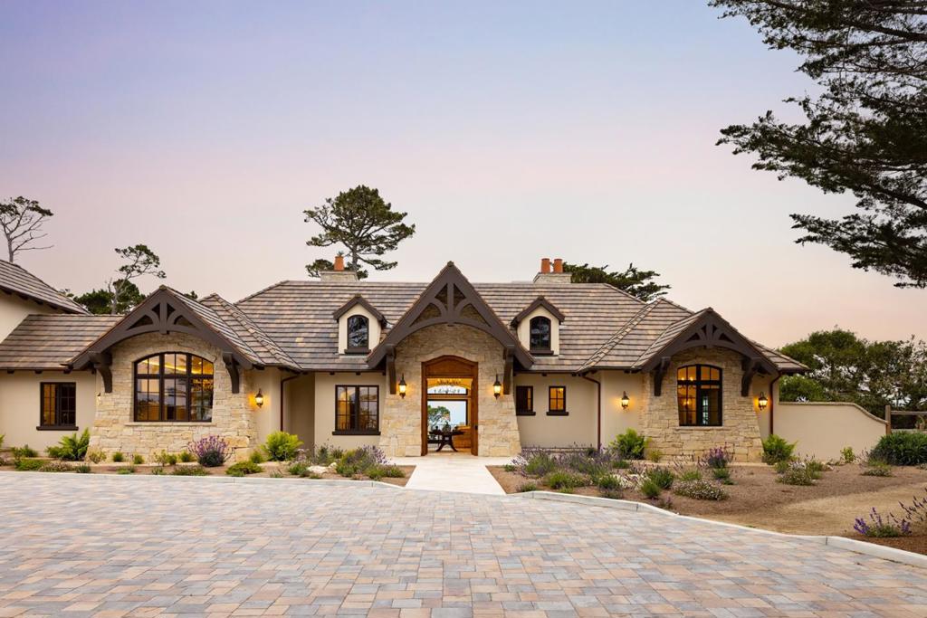 Experience timeless French country elegance at this 6,402+/- sq.ft. estate in Pebble Beach, crafted by Randy Wallis and designed by Jun Sillano of IDG. Set on 1.35 acres with panoramic views from Point Lobos to Point Sur in Big Sur and the coastline in between, this 5-bed, 6.5-bath home offers refined living in a private coastal setting. The stone entry opens to a grand living room with wide-plank wood floors, oak built-ins, and Ironware chandeliers. The gourmet kitchen features honed marble counters, Thermador appliances, a wood-clad hood, and walk-in pantry, all adjacent to a cozy family room with fireplace. A main-level primary suite includes French doors to the deck, walk-in closets, and a spa-like bath with Palomino granite and walk-out patio. Other features include an elevator connecting the main levels, a guest suite with ocean views, and a lower level with game room, multiple ensuite bedrooms, laundry, and radiant heat throughout. The 920+/- sq.ft. 3-car garage has dual EV chargers. Exterior highlights include fire pit, ocean-facing deck, uplighting, bronze railings, and room for a pool or guest unit. Quietly nestled among oaks with privacy and potential for expansion, this is Pebble Beach luxury at its finest.