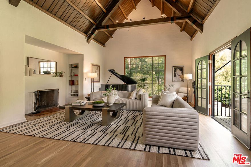 As one of Hollywoodland's original landmark homes, this French Normandy Revival c. 1927 holds a place of distinction among the storied hills. Designed by Hollywood architect Charles David Grolle, this exquisite property is set on two lush lots with a mini vineyard and totaling nearly half an acre of manicured grounds. From the moment you arrive, the home's craftsmanship and architectural pedigree are undeniable. The journey begins with a grand entry spiral staircase leading to a formal dining and great room. The residence then unfolds across three en-suite bedrooms. There is also a private entry-1 bedroom, 1 bath studio with recording space, that has over the years hosted a long list of celebrated recording artists including Wendy & Lisa, Prince, Grace Jones, Seal, Steve Perry and countless others. Discover beautifully refinished hardwood floors, custom kitchen with porcelain tile and Viking appliances, colorful stained-glass windows, arched windows and period light fixtures throughout. Plum, pomegranate, Fuji apple and avocado trees adorn this sweeping street-to-street lot with multiple outdoor spaces, two custom gated entries, a bonus art studio, expansive red oak deck, stone walls, gravel paths and endless hillside views. This is a rare opportunity to own an authentic piece of Los Angeles' golden era of design. First time on the market in 40 years, living here means becoming part of a neighborhood that values preservation, beauty, and the unique character that has defined Hollywoodland for nearly a century.