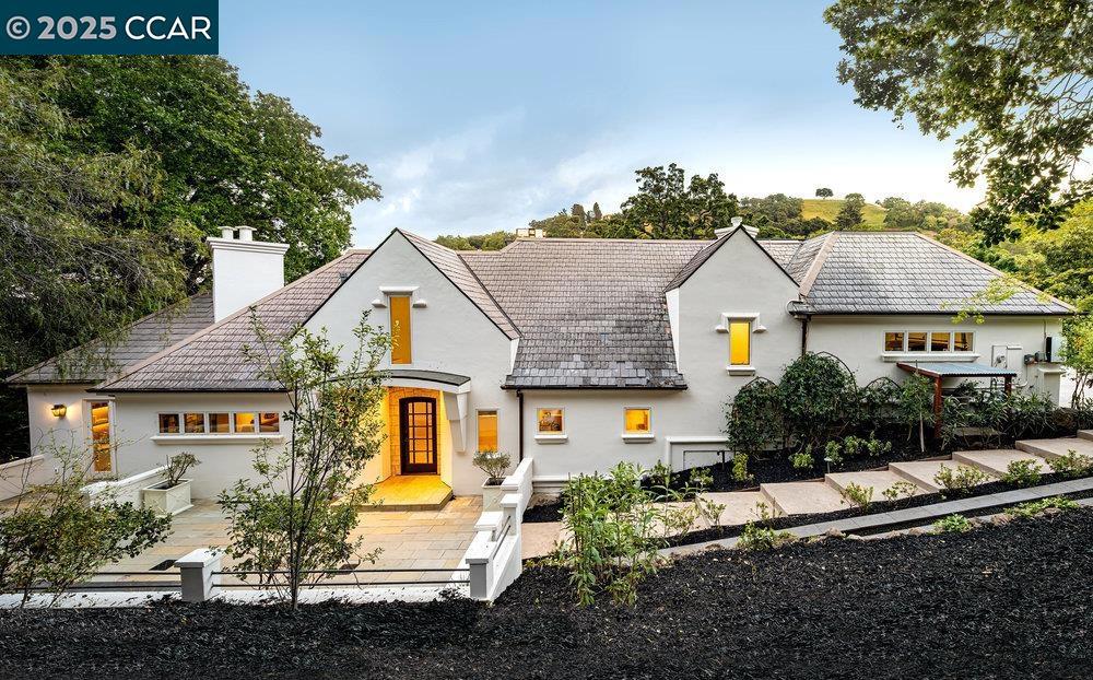 This Reliez Valley home is a private sanctuary. The main level offers formal spaces to the left and casual spaces to the right, linked by French oak hardwoods. The 384-sq-ft living room has a limestone fireplace. The dining room alongside welcomes 10-12 guests under elevated ceilings. The spacious family room also has a soaring ceiling. Nearby, a breakfast nook provides garden and pool views. Between sits the kitchen, with elite appliances, countertops, an island and bar seating. For entertainment, the home offers an 85” TV and sound system, and a spectacular 400-sq-ft cinema. A large office on the main level makes work from home easy. The 5 bedrooms are on the lower level, ensuring privacy. The principal suite is a serene haven with a custom fireplace, garden views, deck access, walk-in closet, and a spa-like bath. A second principal suite has its own en-suite bath, closet with built-in desk, and deck access. An au pair suite (now configured as a gym), with a separate entrance, completes the floor. The outdoor dining terrace seats 12-14 by a fireplace. Just steps below lie the lush lawn and heated pool and sun deck. A slate roof offers enhanced fire resistance. Although just 2 miles from Springhill Elementary and Acalanes High, the home feels a world apart, surrounded by nature.