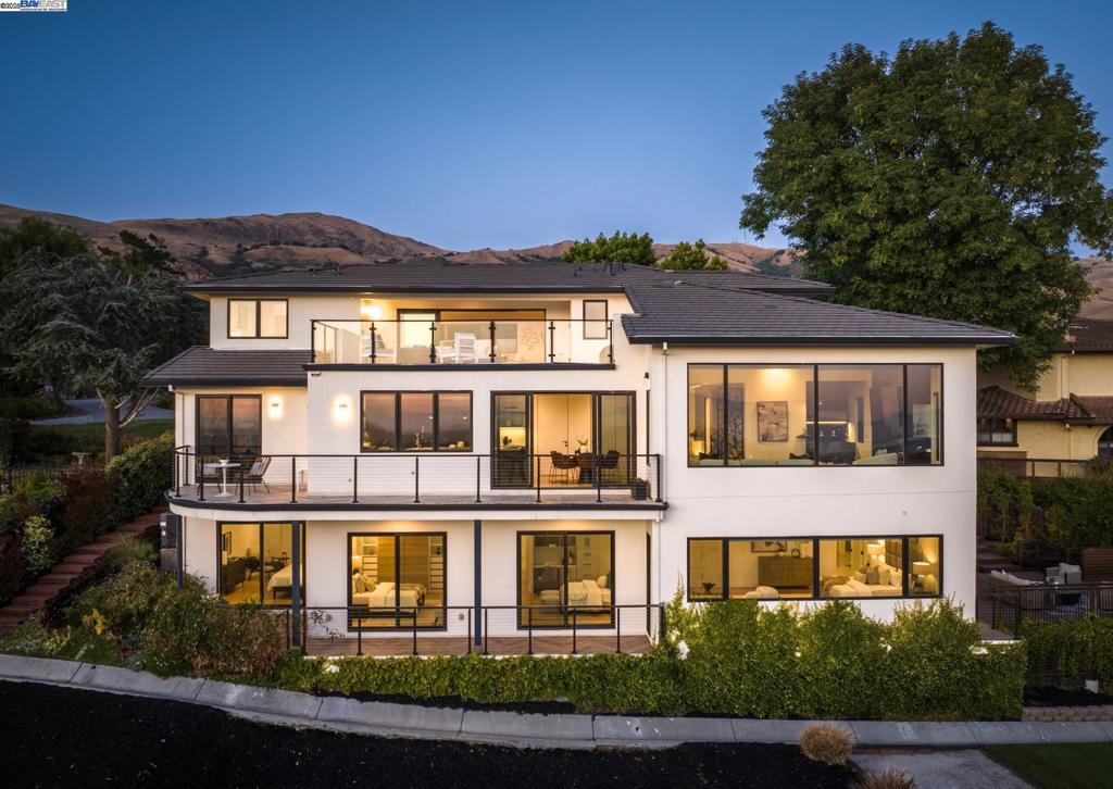 Situated in the exclusive gated community of Vineyard Heights, this architectural masterpiece offers unmatched quality, sleek design, and panoramic Bay views. This 5-year new construction, designed by a renowned architect, features 5 bedrooms, 5 full bathrooms, 3 powder rooms, and a private elevator for seamless access across all 4,983 sf. The open-concept layout centers around a stunning great room with a fireplace and expansive walls of glass that frame sweeping Bay views. It adjoins a gourmet kitchen with dramatic three-tone European cabinetry, quartz countertops, and top-tier Thermador appliances. Natural light floods every corner, with seamless flow to patios and entertainment areas. The primary suite boasts a private terrace, spa-inspired bath, and custom walk-in closet. Additional highlights include smart home tech, a dedicated office, a bonus/media room, and a Bayview sky terrace adjoining the bonus room. The side yard is designed for refined outdoor living, featuring premium decking ideal for entertaining, and lush turf for effortless elegance and low-maintenance beauty. Enjoy majestic views of Mission Peak and walkable access to its scenic trails. All minutes from top schools, parks, and major tech campuses, with a spacious 3-car garage.
