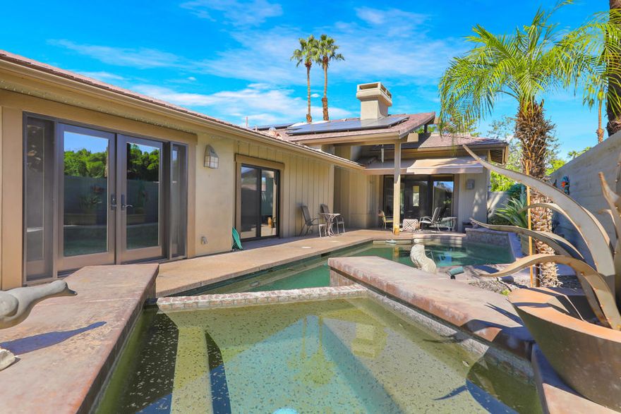 This expanded Santa Fe floor plan at The Lakes Country Club offers over 3,200 sq. ft. of beautifully designed living space. The home features an added office and an additional bedroom/media room with twin Murphy beds--perfect for guests or flexible use.Walls of windows frame the private pool and spa in your enclosed side yard, while the expanded patio on the golf course side offers a built-in outdoor kitchen and spectacular double fairway views complete with a stone bridge and tranquil water feature. 2 ceiling mounted gas heaters keep this additional entertaining space warm for cool desert nights.  The kitchen has been upgraded with warm rich cabinetry sparing no expense emulating a french farmhouse. Coffered ceilings with in laid ambient lighting is centered over a large two tiered island with creamy countertops on the top tier, while an authentic butcher block lower tier makes this kitchen so fun for any level of cooking!  2 dishwashers for easy clean up.  The primary suite has been expanded with French doors that open to the private side yard, and the remodeled primary bath showcases a sleek, contemporary design with a walk-in, step-free shower. Additional highlights include an enlarged laundry room with extra refrigerator and freezer, an added golf cart garage, and abundant storage throughout--ideal for keeping everything organized and easily accessible.Impeccably maintained, And SOLAR!!!