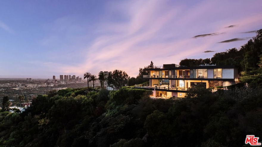 Perched high above the Sunset Strip, 9199 Thrasher Avenue is a turn key architectural masterpiece by internationally acclaimed architect Paul McClean, commanding one of the most dramatic vantage points in all of Los Angeles. Walls of glass frame breathtaking 280 panoramic views that sweep from the shimmering Downtown skyline to the distant coastline of Catalina Island. By day, the residence floats effortlessly above the city; by night, it transforms into a luminous observatory of twinkling lights and endless sky. A grand double-height entry with a 34-foot Murano crystal chandelier adorned with 24K gold leaf and hand-blown glass sets a tone of artistry and sophistication. The open-concept great room flows onto an expansive terrace where a sleek infinity-edge pool and spa appear to dissolve into the horizon. The custom Italian kitchen by ErnestoModa, crowned with a Fendi chandelier and fitted with Miele appliances, is as sculptural as it is functional.Every space has been designed for indulgent living and effortless entertaining  from the glass-enclosed wine cellar, fully equipped gym with horizontal massage shower, and cinematic theater, to the lounge with wraparound fire pit and walls of retractable glass that blur the line between indoors and out. The primary suite is a private retreat with a bar, boutique-style showroom closet, and a spa-inspired bath that captures the essence of luxury resort living. Fully integrated Creston Smart Home technology completes this extraordinary modern sanctuary  a rare opportunity to own a true Paul McClean trophy estate in the Bird Streets.