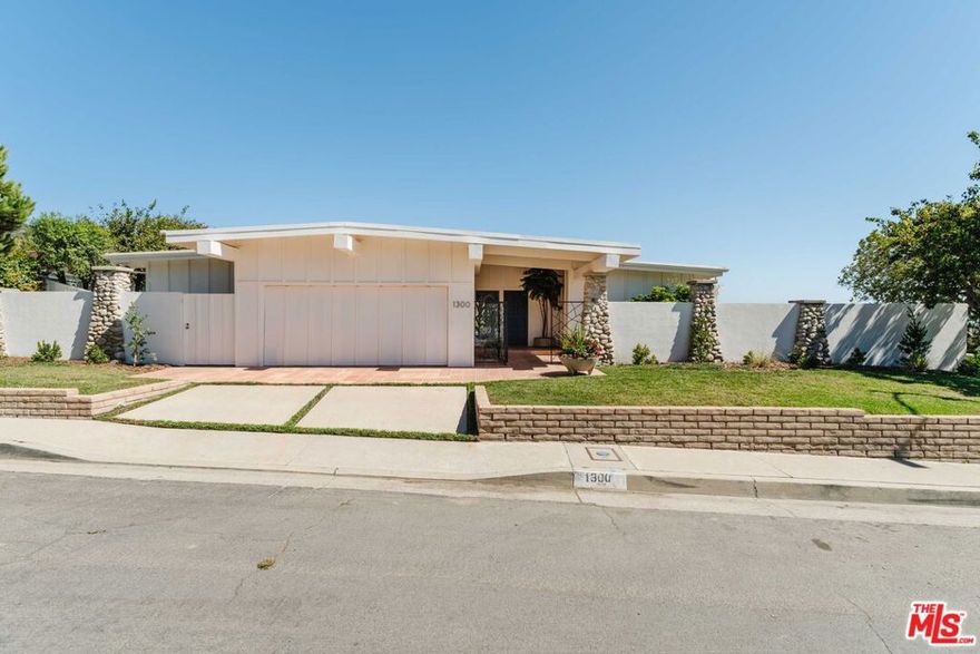 This beautiful, single-level, midcentury residence blends panoramic views from downtown to the coastline and ocean - all on a street-to-street, corner lot set above the neighborhood on an over 12,000-square-foot promontory. Originally designed in 1973 to bring the vistas inside, the home showcases vaulted ceilings with exposed beams, walls of glass, and more. Through the gated entry, guests are welcomed past an outdoor foyer with a water feature into the open layout heart of the home; a formal living room with fireplace, original kitchen, and dining room - all oriented toward the views. Past the den (which could serve as a fourth bedroom), discover three bedrooms, including the primary suite with two closets, a bath with a shower and large vanity, and a private patio overlooking the views. The two guest bedrooms down the hallway share a hall bath with tub. The outdoors wrap around the home with multiple grassy areas, lounging spots, al-fresco dining areas, and newly landscaped grounds that thoughtfully combine mature plantings with fresh additions. Completing the property are a direct-access two-car garage, central air/heat, beautiful tile floors, new carpets in the bedrooms, a powder room, and more. Located off Lachman Lane among many still-standing homes, this stunning residence has been fully remediated and passed post-remediation testing. The property presents an excellent option in its current state, with the added potential to reimagine into the neighborhood's next great home.