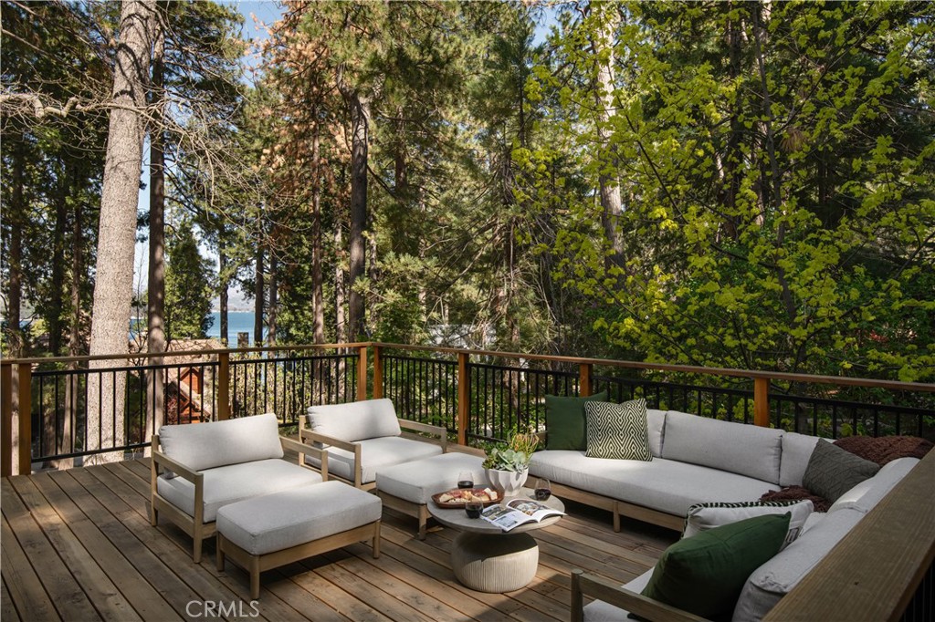 The SkyStone LakeHouse. Welcome to luxurious lake living in the exclusive, guard-gated community of Point Hamiltair—Lake Arrowhead’s most prestigious and sought-after enclave. Known for its 24/7 security, concierge services for home upkeep, and a long-standing legacy of celebrity and socialite residents, this community offers the ultimate in comfort, privacy, and prestige. Located directly across from a $12 million estate and just a short stroll or golf cart ride to your private boat slip, this exquisitely remodeled lakeview home blends timeless mountain charm with top-tier modern upgrades—offering a true turnkey lifestyle.
From the moment you arrive, you’re greeted by breathtaking lake and tree views framed by soaring high-beam A-frame ceilings and an iconic wall of windows. Natural light pours into the open-concept living space, where wide plank European white oak floors and a floor-to-ceiling stone fireplace create the perfect balance of warmth and sophistication. The spacious living area is ideal for entertaining, with abundant seating to relax and soak in the views.
The gourmet kitchen is a designer’s dream, featuring marble countertops, custom cabinetry, a show-stopping Ilve Italian range, European fixtures, and a convenient pass-through shelf that connects directly to the expansive outdoor dining area. Step outside to your wrap-around deck, thoughtfully designed with multiple lounge and dining zones, a built-in BBQ area, and serene spaces to enjoy al fresco meals beneath the stars.
The main-level primary suite is a tranquil retreat with a walk-in closet and spa-inspired ensuite bathroom, complete with marble counters, a custom tile steam shower, and luxury plumbing fixtures. Upstairs, two bright guest bedrooms with vaulted ceilings share a stylish full bath with a walk-in shower and designer vanity. The lower level offers a brick-floored entertainment lounge with a second fireplace, wet bar, game area, ¾ bath, and direct access to the fenced yard and lower patio.
Additional upgrades include a new roof, rebuilt decks and railings, exterior stonework, concrete walkways, professional landscaping, and a subterranean sprinkler system. Offered beautifully furnished (furniture negotiable), this lake view masterpiece is ready to enjoy. A rare opportunity to own in one of Lake Arrowhead’s most iconic and luxurious communities.