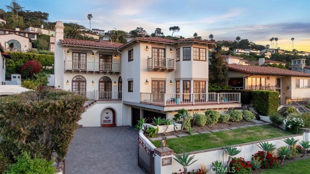 Welcome to 536 Via Media, a timeless coastal retreat in one of the most prestigious enclaves of Palos Verdes Estates—Lower Malaga Cove. Ideally situated just steps from the PV Beach & Athletic Club and RAT Beach, this home offers exceptional walkability and seamless access on and off the Peninsula. Above all, it boasts the view—sweeping, unobstructed panoramas of the Pacific Ocean, Santa Monica Bay, and the iconic Queen’s Necklace by day, transitioning into a dazzling city light display by night.
Originally custom built in 1986 in the quintessential Palos Verdes Spanish style and thoughtfully remodeled since, the home blends classic charm with modern luxury. Recent updates include a beautifully reimagined kitchen and bathrooms, with top-tier Wolf and Sub-Zero appliances, elegant finishes, and refined details. The home is also grandfathered in larger and taller than what would be approved by the PV Homes Association and planning commission today—providing valuable upside not otherwise achievable for similar properties in the neighborhood.
The curb appeal is striking: smooth white stucco, a traditional clay tile roof, arched doorways, and a stately paver driveway anchored by a decorative fountain. A gated entry leads to the main level, where ocean views greet you from nearly every room. The formal living room, with French doors and arched transom windows, opens to the front patio and frames breathtaking views of the coastline. The dining room, adorned with a graceful chandelier, flows into the kitchen with its breakfast nook, marble backsplash, generous counters, and abundant storage. Both spaces open to an expansive brick terrace, perfect for entertaining against a backdrop of ocean vistas and Fourth of July fireworks.
This level also features a guest bedroom and a tastefully remodeled ¾ bath that doubles as the powder room. Upstairs are three en-suite bedrooms and a laundry room with double washers and dryers. Two suites serve as primaries, each showcasing the most dramatic views in the home.
The lower level offers a private one-bedroom suite, mudroom, and access to the spacious three-car garage. The backyard is a true oasis—complete with a built-in BBQ, fire pit, and sparkling pool and spa, all surrounded by lush landscaping on a 6,724 sq ft lot.
With its iconic location, exceptional layout, modern upgrades, and panoramic views, 536 Via Media is a rare offering that captures the very best of Palos Verdes coastal living.