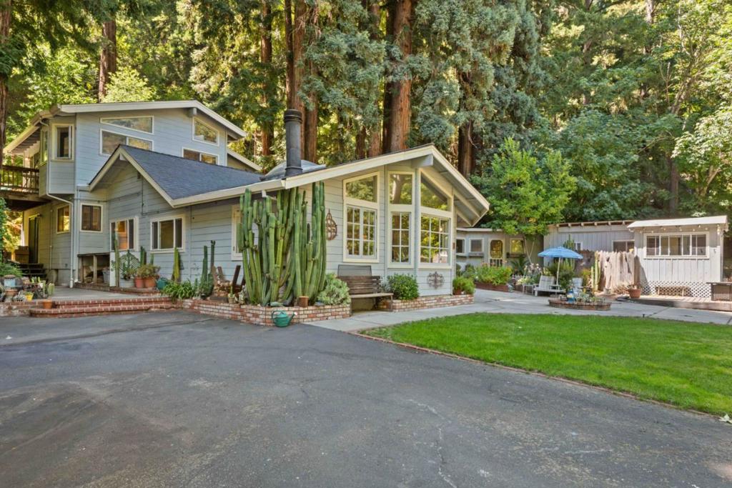Sunlit Scotts Valley Retreat with Guest Cottage! Just 10 minutes from the shops and dining of Scotts Valley and Highway 17, This property blends privacy and country charm,. surrounded by trees and bathed in natural light, The main home features four bedrooms and two bathrooms, including a spacious primary suite with its own private bath, deck and entrance, offering a quiet retreat with tranquil views. The downstairs layout is designed for comfort and function, with a bright great room, office, a cozy family room, a full bathroom, a laundry room, and a warm kitchen that flows naturally for gatherings or everyday living. A detached 1-bedroom, 1-bath guest cottage sits just steps away perfect for hosting extended family, creating a private office, or generating rental income with washer/dryer hooks ups! The grounds are as functional as they are scenic, featuring large creek frontage, two-car garage, 2 custom-built sheds, a carport with added storage, and a wrap-around driveway for easy access and guest parking. An upper gated driveway offers room for an RV, boat, or multiple vehicles, and two more storage units. This one-of-a-kind property offers a rare combination of seclusion and convenience, with abundant sunlight, multiple living options, and a peaceful natural setting.