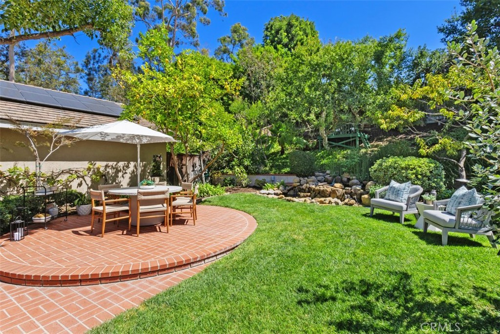 ATTENTION ALL LARGE LOT LOVERS! Tucked away at the end of a quiet cul-de-sac, this meticulously maintained single-level home in the Turtle Rock Glen Patio neighborhood offers nearly 1/4 of an acre of land, privacy in a park-like setting and space for an ADU! The highlight of the backyard is a striking rock waterfall, creating a peaceful retreat that is your own sanctuary.
Designed with entertaining in mind, the floor plan flows effortlessly with walls of windows framing lush greenery and vaulted ceilings that add volume and light. Coveted tri-folding doors off the family room open to the backyard, blending indoor and outdoor living for gatherings large or small.
The backyard is truly a showpiece—perfect for hosting barbecues, birthday parties or simply enjoying quiet evenings. Kids will love the shady deck built into the rear slope, while friends and family can relax on the lawn and patio areas. Multiple fruit trees provide fresh seasonal harvests, making the yard both beautiful and functional. Inside, an inviting atrium connects to three areas of the home, offering a sunlit retreat and a safe haven for pets.
The layout includes a living room with a fireplace and adjoining dining room, ideal for everyday living and entertaining. A well-appointed kitchen showcases white custom cabinetry, granite counters, LED recessed lighting, stainless steel appliances, gas cooktop and dual pantries. Retreat to the primary suite with vaulted ceilings, skylight and access to the atrium. The remodeled spa-inspired bathroom features dual vanities, soaking tub, separate shower, dual mirrored closets and a private toilet room. Adjoining the suite is an office/exercise room or 4th bedroom. Two additional bedrooms share a well designed hallway bath with dual sinks, built-in hamper, a private washroom, and a remodeled shower.
Energy-efficient features and upgrades abound: owned solar panels, Pella dual-pane windows, concrete tile roof, newer HVAC & ducts, LED lighting, copper re-pipe, engineered wood flooring, 11 skylights, 2 fireplaces and an EV charger.
Walk to award-winning Turtle Rock Elementary & University High School. Easy access to resort-style community pools, tennis courts, playgrounds, scenic greenbelt and biking trails. Just a few minutes to world-class beaches, golf, shopping, restaurants, John Wayne Airport and freeways. Low taxes, no Mello Roos and low HOA dues add to the value.
This is more than a home—it’s a lifestyle that’s waiting for you!