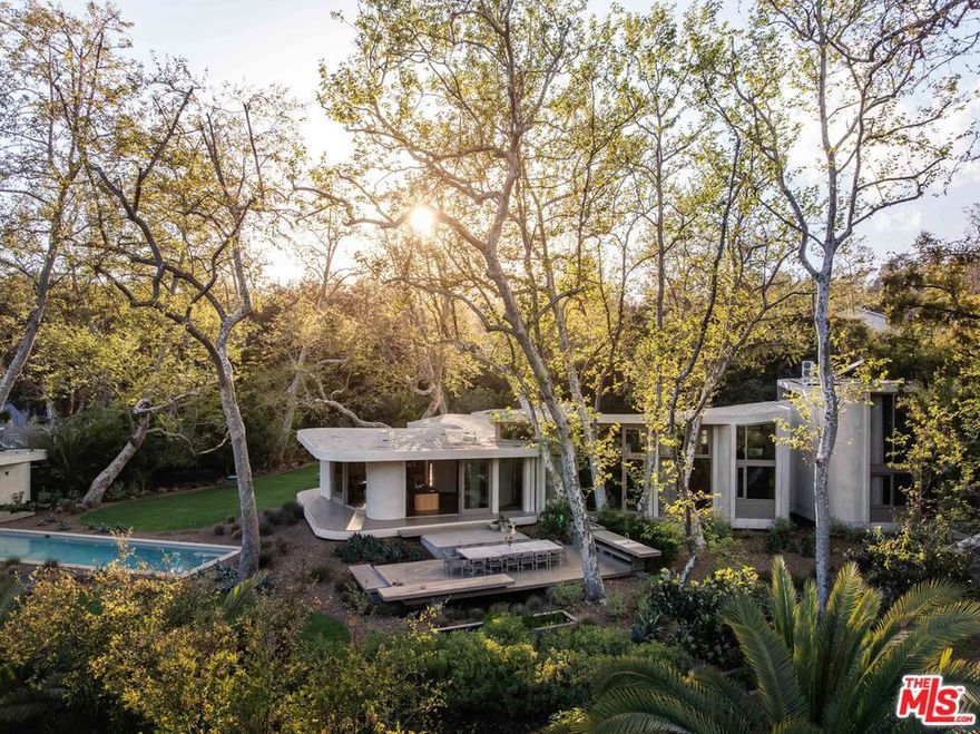 A custom-built sanctuary on over an acre in Rustic Canyon, 800 Brooktree Road's thoughtful, meticulous design surpasses all expectations. Spanning 9,708 square feet across two levels with 8 bedrooms and 6.5 baths, this home was designed by architect Bill Neburka to embrace curves, soft lines and have an inviting natural palette. Living spaces both indoor and outdoor have been crafted to maximize comfort and harmonize with the verdant surroundings. Once inside, guests are greeted with floor-to-ceiling windows framed in natural wood hues, which showcase stands of mature native trees more than 20 sycamore and coastal oaks grow on the carefully maintained property. The estate's entrance also presents hand-fired tile and an abstract sycamore installation by artist Sofia Londono, setting the stage for the home's nature-centric ambiance. Interiors by designer Jeff Guga boast soaring ceilings, wide-plank white oak hardwood floors, and soft-hued walls finished in hand-troweled Clayworks plaster. Organic materials throughout the homewood, clay and brasswere hand-selected for their warmth and durability. Custom lighting, including skylights with color LEDs, enhance the home's abundant natural light. Curated finishes include Heath floor tiles made in California, hand-crafted brass plumbing fixtures by Vola and Reveal lift and slide doors. The chef's kitchen, music room and living room (replete with 15-foot ceilings) each face a stunning grove of sycamores, while the primary bedroom overlooks a stand of coastal oaks. Outside, find expansive Alaskan cedar decks, which look out on a divine landscape designed by Jay Griffith, as well as a 60-foot saline lap pool and a standalone pool house complete with an additional bedroom and full bath. Two nearby creeks add a soothing soundtrack of flowing water throughout the year and charming frog songs in the summer. Built to last with enduring modern design and unparalleled craftsmanship, 800 Brooktree Road couples peaceful daily living with true convenience. Its ultra-private location is less than 5 minutes from the beach, Palisades Park, and the shops and restaurants of Montana Avenue and Downtown Santa Monica.
