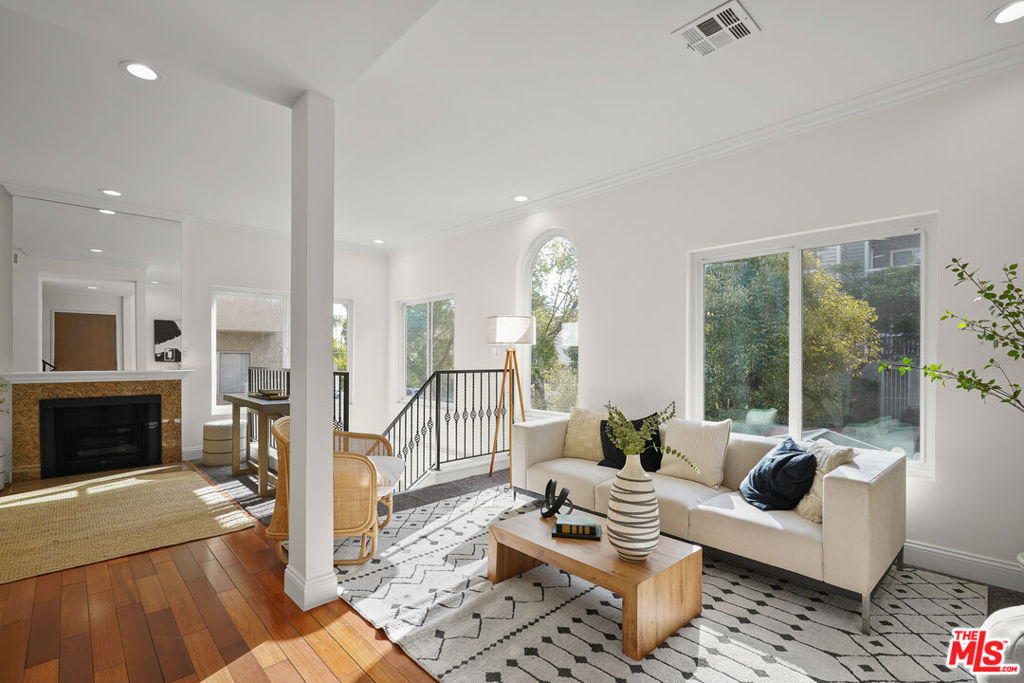 This highly desirable, rarely available, airy, and spacious three-level, five-bedroom home is a standout with a high walk score of 90! Incredible value awaits at this updated townhome-style residence, a dream come true, perfect for large and growing families, multi-family or multi-generational living, guests, roommates, or anyone who would like to rent one of the spaces for additional income. Welcome to a single-family alternative in a well-maintained building, the only of its kind and essentially two homes in one, with two full kitchens, three separate private entrances, and unlimited possibilities. With only one shared common wall, the original 1990 build recently underwent a full-conversion, top-to-bottom remodel. The main home is light-filled with large windows showcasing lush treetops and greenery. The bright living room features a traditional granite fireplace, wet bar, and gleaming wood floors that flow into the dining room, and the kitchen has stainless-steel appliances and plenty of storage space. Upstairs, bedrooms are spacious, with two having their own private balconies overlooking this desirable neighborhood. On the first level, the secondary living quarters offer a self-contained retreat. This space includes a cozy living room, a versatile sitting room ideal for an office, a full kitchen with stainless-steel appliances and breakfast bar, a dining area, two bedrooms, and two full bathrooms, all perfect for extended family, guests, or rental opportunities. There is also gated, controlled-access parking as well as dual HVAC units for split-level cooling and heating plus dual-pane windows for noise and temperature control. Ideally located at the edge of Beverly Hills with a high walk score, this wonderful home is near synagogues, parks, schools, grocery stores, eateries, and more.
