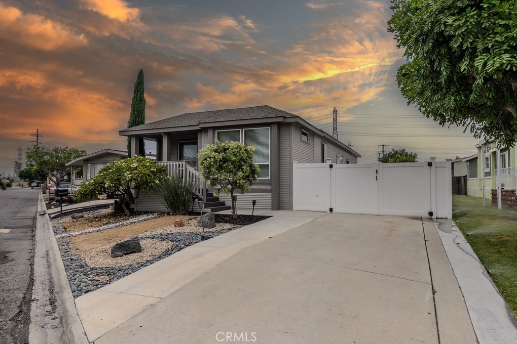 3595 Santa Fe Ave #278, Long Beach, located in Windward Village, a community of manufactured homes with land ownership. Built in 2017, this three-bedroom, two-bath home is set on one of the largest lots in the community at 5,719 square feet. Positioned on a corner lot for added privacy, it features a covered front porch and landscaped entry that create strong curb appeal. A wide driveway, plus gated side parking for up to four cars, adds versatility. Inside, the entry opens to a spacious great room where the living room, kitchen, and dining area connect under 9-foot ceilings with recessed lights, skylights, and laminate wood flooring. The kitchen features a waterfall quartz island with seating, a built-in microwave drawer, pull-out storage drawers, a stainless steel range with double oven, a pot filler faucet, a range vent, under-cabinet lighting, a farm sink, a walk-in pantry, and ample cabinetry. The dining area sits in a cove off the kitchen, while the living room offers a ceiling fan, built-in lower cabinets, and a stacked stone accent wall. The primary bedroom includes a ceiling fan, a walk-in closet with a solar tube, and a sliding glass door to the backyard. The en suite bath has dual sinks, stone counters, linen cabinets, a deep soaking tub, and a walk-in tiled shower with a seating bench. Two additional bedrooms offer carpet, ceiling fans, and wall outlets ready for mounted televisions. The guest bath includes a walk-in tiled shower with a seating bench and stone counters. The laundry room is inside, with cabinets for storage. The backyard is larger than typical for the community, with newer vinyl fencing for privacy, an automated sprinkler system, and ample space for outdoor seating or gardening. The front yard has a drip irrigation system, and the home includes an electric car charger. HOA amenities include gated entry with 24-hour security, clubhouse, pool and spa, tennis and basketball courts, fitness center, playground, RV storage, recreational areas, billiard room, and landscaped grounds. HOA dues are $330 per month.