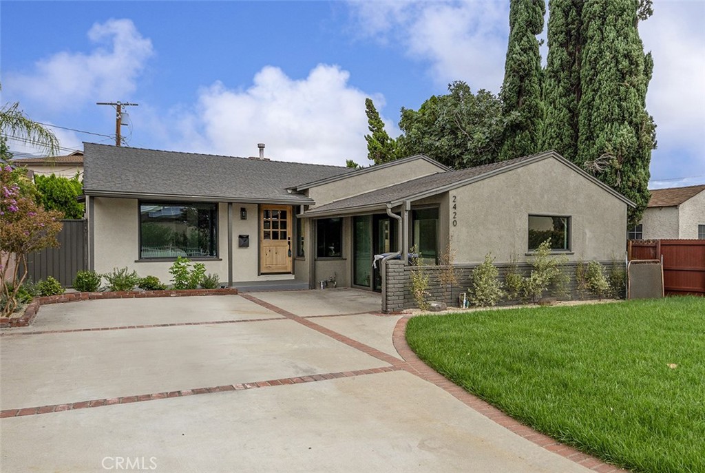 Tucked away on a picturesque, tree-lined street in the desirable Burbank foothills, this beautifully renovated modern traditional home blends timeless charm with contemporary elegance. From the moment you step inside, you're greeted by an expansive open-concept layout featuring a dramatic decorative brick fireplace with a custom wood mantel—setting the tone for stylish, comfortable living. The chef’s kitchen is a true showpiece, complete with sleek countertops, designer tile backsplash, custom cabinetry, and top-of-the-line stainless steel appliances. Perfect for both entertaining and everyday living, the seamless indoor-outdoor flow is highlighted by sliding glass doors that lead to a spacious deck and a generous, grassy backyard—ideal for gatherings or quiet relaxation. A set of modern barn doors just off the main living area opens to a flexible bonus room, perfect for a home office, playroom, or guest space. The tranquil primary suite offers direct access to the backyard, a custom-organized closet, and a luxurious ensuite bath featuring a dual-sink vanity, glass-enclosed shower, and a deep soaking tub for spa-like indulgence. Two additional bedrooms at the front of the home share a beautifully updated full bath, providing ample space for family or guests. Outside, the fully fenced and gated backyard offers multiple zones for entertaining, play, or future pool/spa addition. A detached two-car garage completes this exceptional offering. Located in one of Burbank’s most coveted neighborhoods—just moments from top-rated schools, major studios, shopping, dining, and commuter routes—this is California living at its finest.