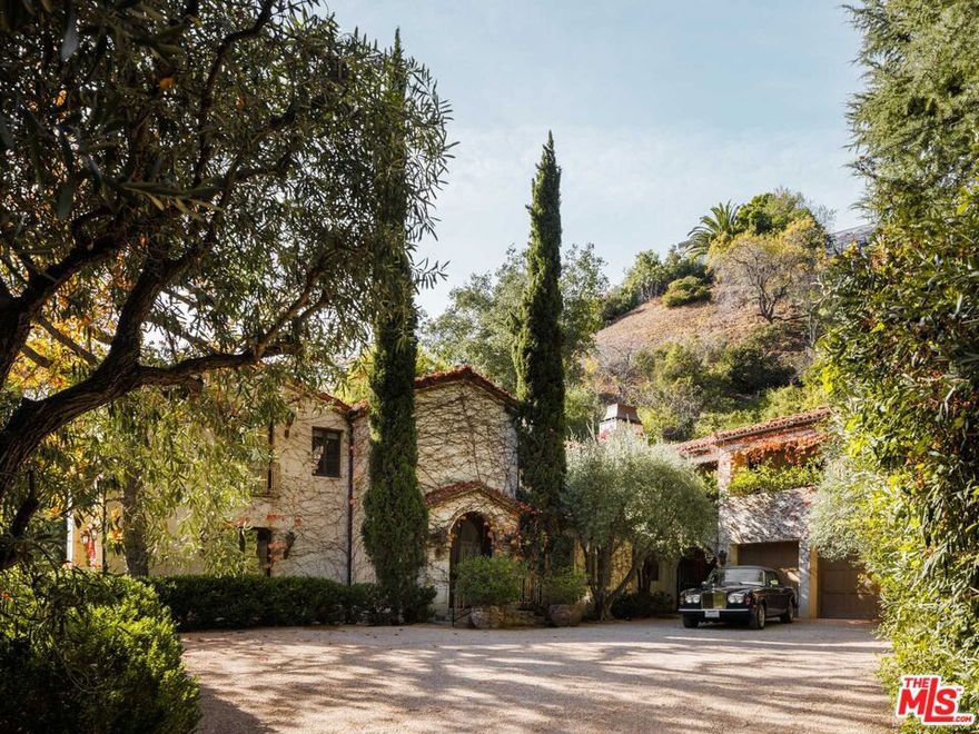 Chic European elegance awaits within 9606 Heather Road. Boasting over two acres of picturesque grounds, this property provides two distinct residences, each accessible via separate street entrances. Guests are greeted by a grand gate and a majestic tree-lined driveway. The vine-covered facade immediately enchants, surrounded by filtered light through lush greenery. It's a true storybook setting. Every room within the main residence exudes sophistication, adorned with lofty ceilings and impeccable finishes. The living room features gorgeous beamed ceilings, arched doorways leading from room to room, and expansive windows looking out onto the surrounding beauty. Step outside to discover the estate's meticulously manicured gardens, sparkling pool, and charming pool house. Numerous patios and seating areas provide ideal settings for gatherings and al fresco dining.A 2100-square-foot guest house, accessible from both the main property and its own distinct address, completes this exceptional compound. Take in garden views from walls of glass and enjoy a private patio. Situated just minutes from downtown Beverly Hills, this sanctuary offers the epitome of luxury living in an unparalleled location.