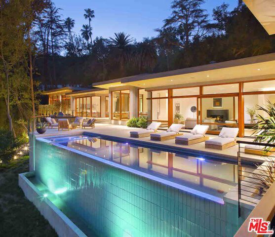 This exquisite modern estate redesigned and completed in 2016 offers private serenity on just under an acre of wooded grounds up the street from the Beverly Hills Hotel. Expanded from the original, this sprawling 11,300 sq. ft. mostly single level home, shows great respect and integrity for the original architecture and the land upon which it sits. The master suite is a home of its own, with a large 3-sided floating fireplace wall and executive kitchen, huge his and her master bathrooms with a solid Calcutta wall with his and her showers opening to a zen courtyard. The master bathroom also has dual exquisite closets, dual Toto toilets, and large soaking tub with ceiling waterfall feature. This exquisite piece of dramatic contemporary architecture is a rare paradise that allows you to hide in plain site while enjoying the benefits of living in the heart of the city.