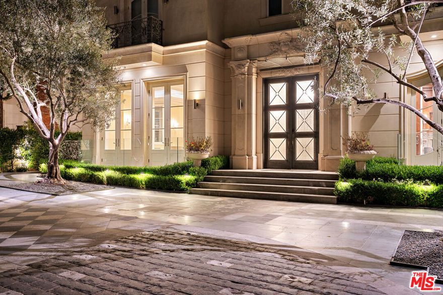 Completed in 2017, this newly furnished masterpiece blends timeless European architectural influences with the most advanced modern comforts, including full Crestron smart home integration. Spanning approximately 12,000 feet with three expansive levels serviced by an elevator, this 7-bedroom compound (including a separate guest house) features bespoke finishes throughout and is newly outfitted with Restoration Hardware furnishings. At the heart of the home is an oversized chef's kitchen with top-of-the-line Miele, Wolf, and Sub-Zero appliances including a double-sided refrigerator, four freezers, 8-burner range, dual ovens, and built-in espresso machine centered around a massive island ideal for culinary creativity and social gatherings. Unwind in the spectacular diamond-quilted leather theater with 14+ plush seats and state-of-the-art audiovisual technology. Entertain effortlessly with indoor-outdoor flow, outdoor poolside shower and bathroom, barbecue area, and multiple balconies. Indulge in spa-like amenities including a rare indoor saltwater pool with swim current jets, rainfall shower, and both dry and wet saunas. A custom wine cellar, lavish primary suite with oversized walk-in closet and jacuzzi, and smart security system with full perimeter cameras, motion detectors, and glass-break sensors complete the experience. Additional features include water softening and reverse osmosis filtration systems, garage parking, and a separate guest house ideal for staff, guests, or a private home office setup. This one-of-a-kind estate is offered fully furnished and move-in ready. Experience luxury living at its finest, in the most prestigious location Beverly Hills has to offer.