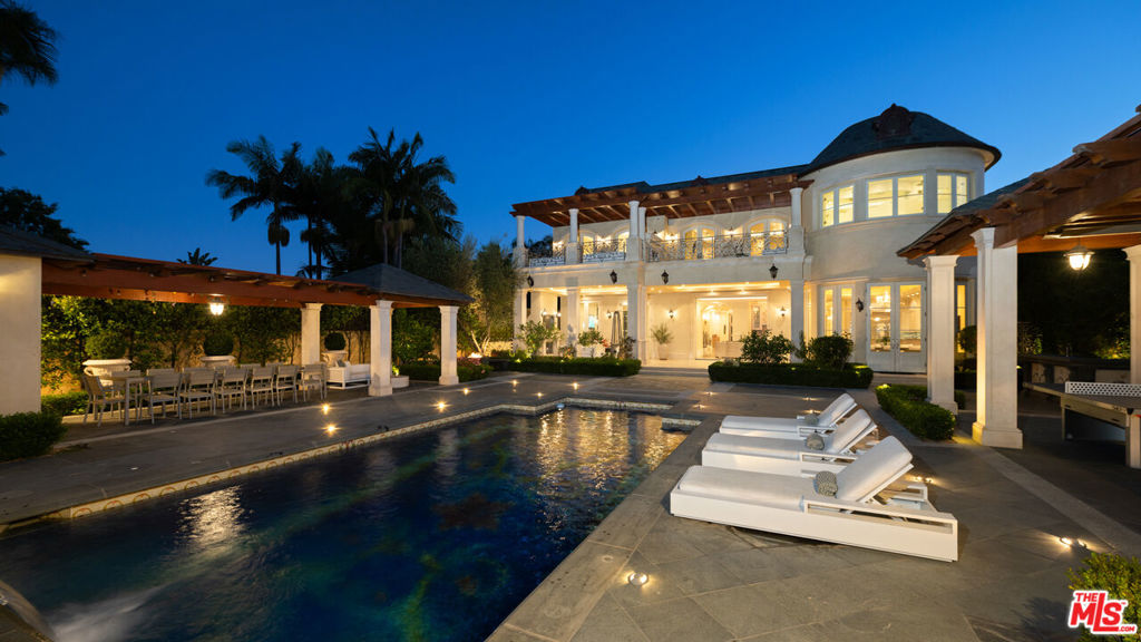 Completed in 2017, this newly furnished masterpiece blends timeless European architectural influences with the most advanced modern comforts, including full Crestron smart home integration. Spanning approximately 12,000 feet with three expansive levels serviced by an elevator, this 7-bedroom compound (including a separate guest house) features bespoke finishes throughout and is newly outfitted with Restoration Hardware furnishings. At the heart of the home is an oversized chef's kitchen with top-of-the-line Miele, Wolf, and Sub-Zero appliances including a double-sided refrigerator, four freezers, 8-burner range, dual ovens, and built-in espresso machine centered around a massive island ideal for culinary creativity and social gatherings. Unwind in the spectacular diamond-quilted leather theater with 14+ plush seats and state-of-the-art audiovisual technology. Entertain effortlessly with indoor-outdoor flow, outdoor poolside shower and bathroom, barbecue area, and multiple balconies. Indulge in spa-like amenities including a rare indoor saltwater pool with swim current jets, rainfall shower, and both dry and wet saunas. A custom wine cellar, lavish primary suite with oversized walk-in closet and jacuzzi, and smart security system with full perimeter cameras, motion detectors, and glass-break sensors complete the experience. Additional features include water softening and reverse osmosis filtration systems, garage parking, and a separate guest house ideal for staff, guests, or a private home office setup. This one-of-a-kind estate is offered fully furnished and move-in ready for long-term or multi-month lease. Experience luxury living at its finest, in the most prestigious location Beverly Hills has to offer.