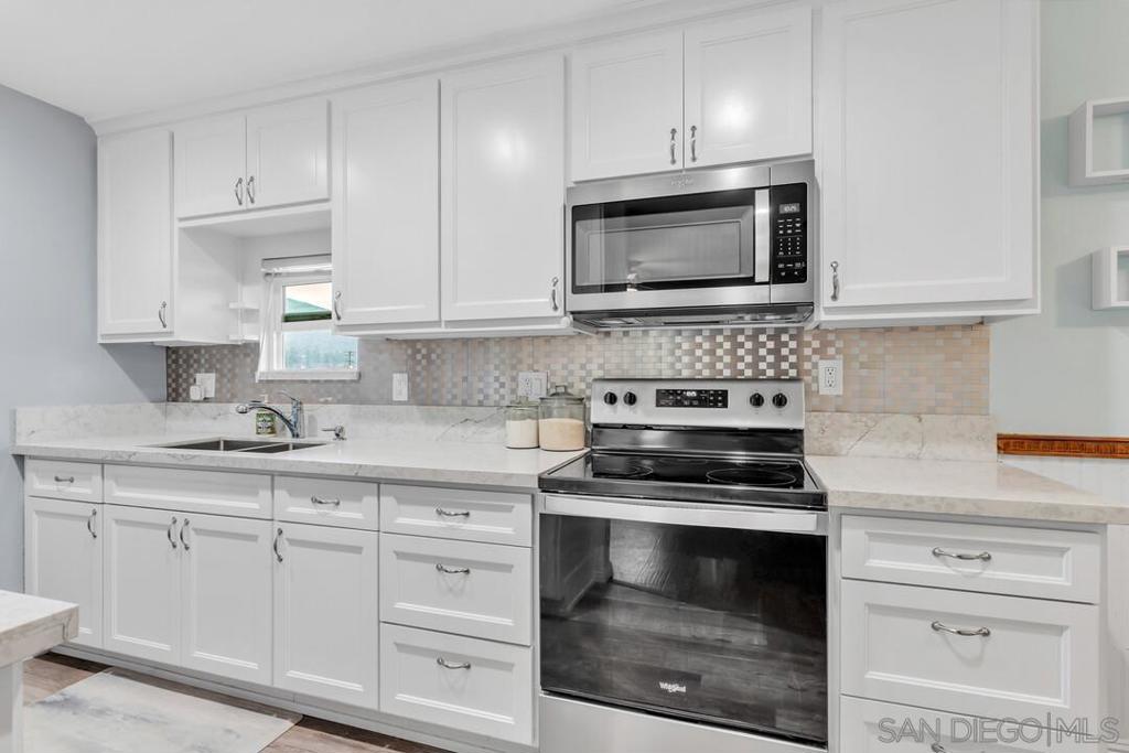 This beautifully updated 2-bedroom, 2-bathroom condo offers modern upgrades and a rare set of features located within a private gated community. The kitchen features quartz countertops, durable vinyl plank flooring, and stainless steel appliances. A standout feature of this unit is the indoor washer and dryer, an added convenience not commonly found in other units. Extra windows in the kitchen and bathroom bring in natural light, enhancing the overall living experience. Situated in a private rear corner of the complex, this unit provides added tranquility along with beautiful views of Palomar Mountain from the kitchen. The spacious front deck/patio is perfect for relaxing or entertaining, with plenty of room for a BBQ and seating area. Residents can enjoy a range of community amenities, including a swimming pool and racquetball courts. The unit comes with two parking spaces—one covered assigned space with spacious overhead storage and one unassigned uncovered space. Conveniently located near freeway access for easy commuting.