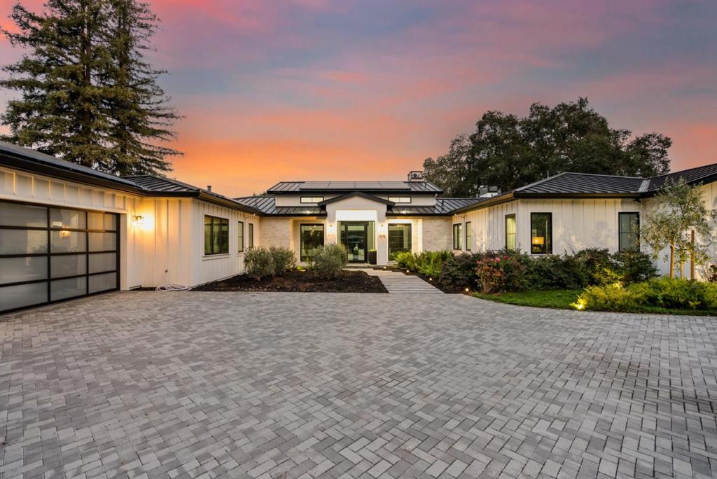 Completed in 2019, and significantly upgraded since then, this home is a masterfully modern interpretation of the classic farmhouse. Secure perimeter fencing & a set-back location from the street offer abundant privacy. A state-of-the-art voice-activated home automation system, electronically controlled window blinds, tinted front windows, & Restoration Hardware lighting are just some of the many recent upgrades. Solar powers electricity & the pool, and 4 Tesla Powerwalls were added for uninterrupted backup. The sleek, two-story design is flexible and open with a strong connection to the outdoor spaces and a wonderful sense of volume with ceilings that reach almost 15 feet. White oak floors tie every room together in quiet harmony, picture windows and transoms fill the home with natural light, and the entire design follows a minimalist perspective. The lower level comprises a wonderful recreation area with full bar and significant wine storage, a fitness center, cinema-quality theatre.