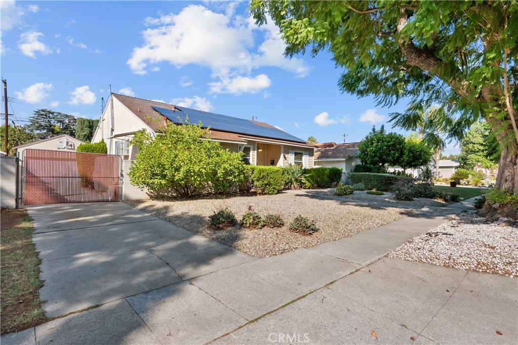 Tucked away on a quiet, tree-lined street in the sought-after Granada Hills neighborhood, this delightful mid-century home offers the perfect combination of vintage character and modern upgrades. Surrounded by a friendly, well-kept community, this home is ideal for comfortable family living. A welcoming front porch leads into a warm and inviting interior featuring hardwood floors, abundant natural light, and timeless architectural details throughout. With three bedrooms and two bathrooms, this home provides generous space for both relaxing and entertaining. The heart of the home is the remodeled cook’s kitchen, showcasing recessed lighting, crisp white shaker cabinets, quartz countertops, and a classic subway tile backsplash. Quality appliances include a gas range with vent hood, dishwasher, and refrigerator. Just off the kitchen is a functional laundry room with storage and access to the side yard. The cozy living room connects seamlessly to a dedicated dining area, accented by hardwood flooring and a ceiling fan light fixture—perfect for daily meals or festive gatherings. A spacious family room features wood-beamed ceilings, a brick fireplace, and sliding doors that lead to a private backyard, blending indoor comfort with outdoor living. The spacious primary bedroom offers hardwood floors, dual closets, and an en-suite bathroom with a tiled stall shower and separate vanity. Two additional bedrooms are bright and well-sized, each with ceiling fans, hardwood floors, and ample closet space. A full hallway bathroom with a tiled shower-over-tub and a vanity serves these rooms. Step outside to the private backyard with a sprawling lawn and mature greenery—an ideal space for entertaining, play, or peaceful retreat. The extended concrete driveway and detached two-car garage offer abundant parking and storage. Thoughtful upgrades include central air and heat, dual-pane windows, mostly copper plumbing, and an owned energy-efficient solar system for lasting savings. The large backyard with detached garage provides excellent potential for a freestanding Accessory Dwelling Unit (ADU). Conveniently located near schools, shopping, dining, and freeway access, this move-in ready gem combines classic style with today’s comforts—ready for you to call home.