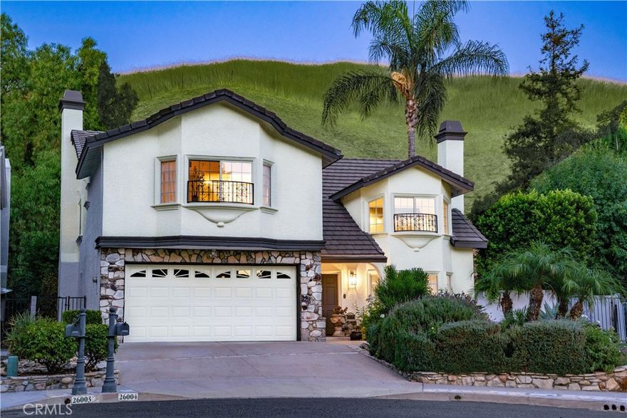 Located in one of Calabasas’ most desirable neighborhoods and within the award-winning Las Virgenes Unified School District, assigned to highly rated schools including Lupin Hill Elementary, A.E. Wright Middle, and Calabasas High, this 4-bedroom, 2.5-bathroom home offers nearly 2,500 sq ft of living space on an expansive 13,255 sq ft lot. Nestled at the end of a peaceful cul-de-sac and surrounded by rolling hills with striking mountain views, the property provides both privacy and an ideal family-friendly setting. Double doors open to a dramatic foyer where a grand staircase, soaring ceilings, and travertine floors with custom inlays create a striking first impression. The formal living room features a vaulted beamed ceiling, centerpiece fireplace, and floor-to-ceiling windows that bathe the space in natural light, flowing seamlessly into the formal dining room with a tray ceiling and backyard views. The gourmet kitchen boasts granite countertops, stainless-steel appliances including a 6-burner Viking range with double oven and matching hood, and a breakfast peninsula that opens to the inviting family room with its own fireplace and French doors to the outdoors. Designed for entertaining, the backyard is a private paradise with a built-in barbecue, lush lawn, sparkling pool and spa with cascading waterfalls, and mature tropical landscaping set against a backdrop of hillsides and treetops. Completing the main level are a powder bath, laundry room, and direct access to the attached 2-car garage. Upstairs, a spacious landing overlooks the living room and leads to four bright bedrooms, each with hillside or mountain views. The primary suite features vaulted tray ceilings, a bay window nook, walk-in closet, and a beautifully upgraded en-suite bath showcasing marble flooring, artisan tile work, and dual sinks, while the secondary bedrooms share a well-appointed hall bath with a dual vanity and matching upgrades of marble and artisan tile finishes. All this is just minutes from The Commons at Calabasas, the Civic Center, local dining, hiking trails, and convenient freeway access, offering the perfect blend of comfort, convenience, and resort-style living.